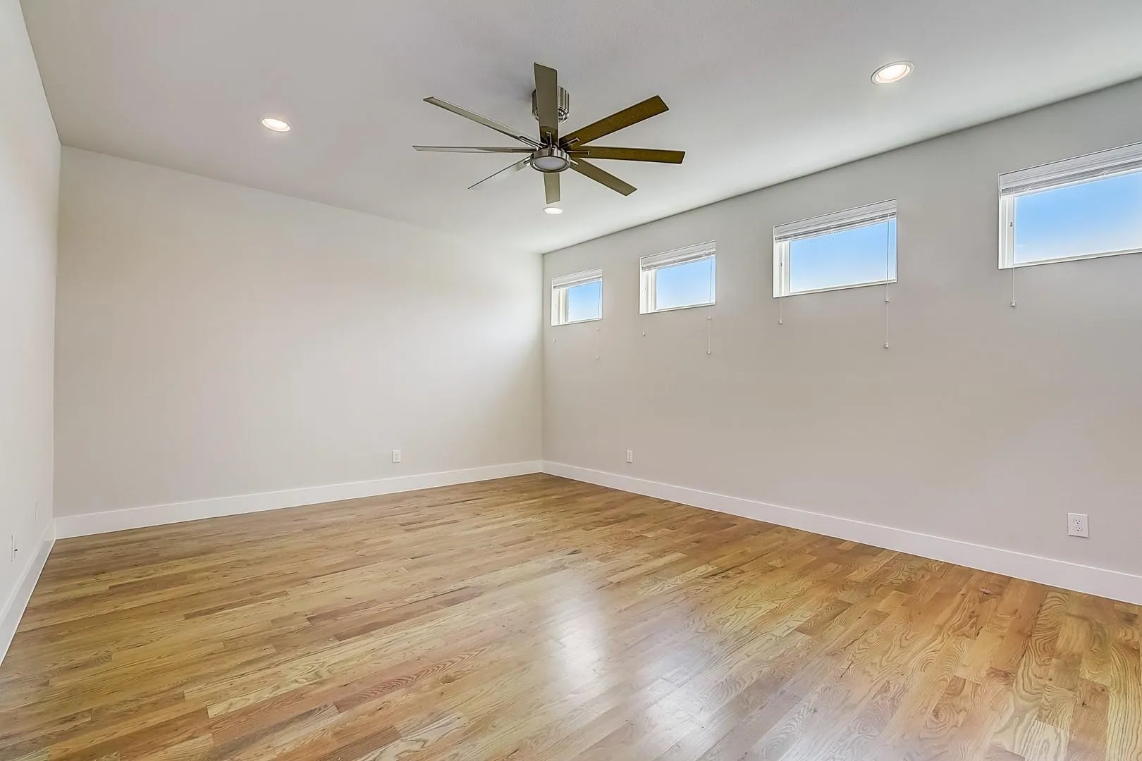 Wood-finish flooring, recessed lighting, ceiling fan, and multiple transom windows
