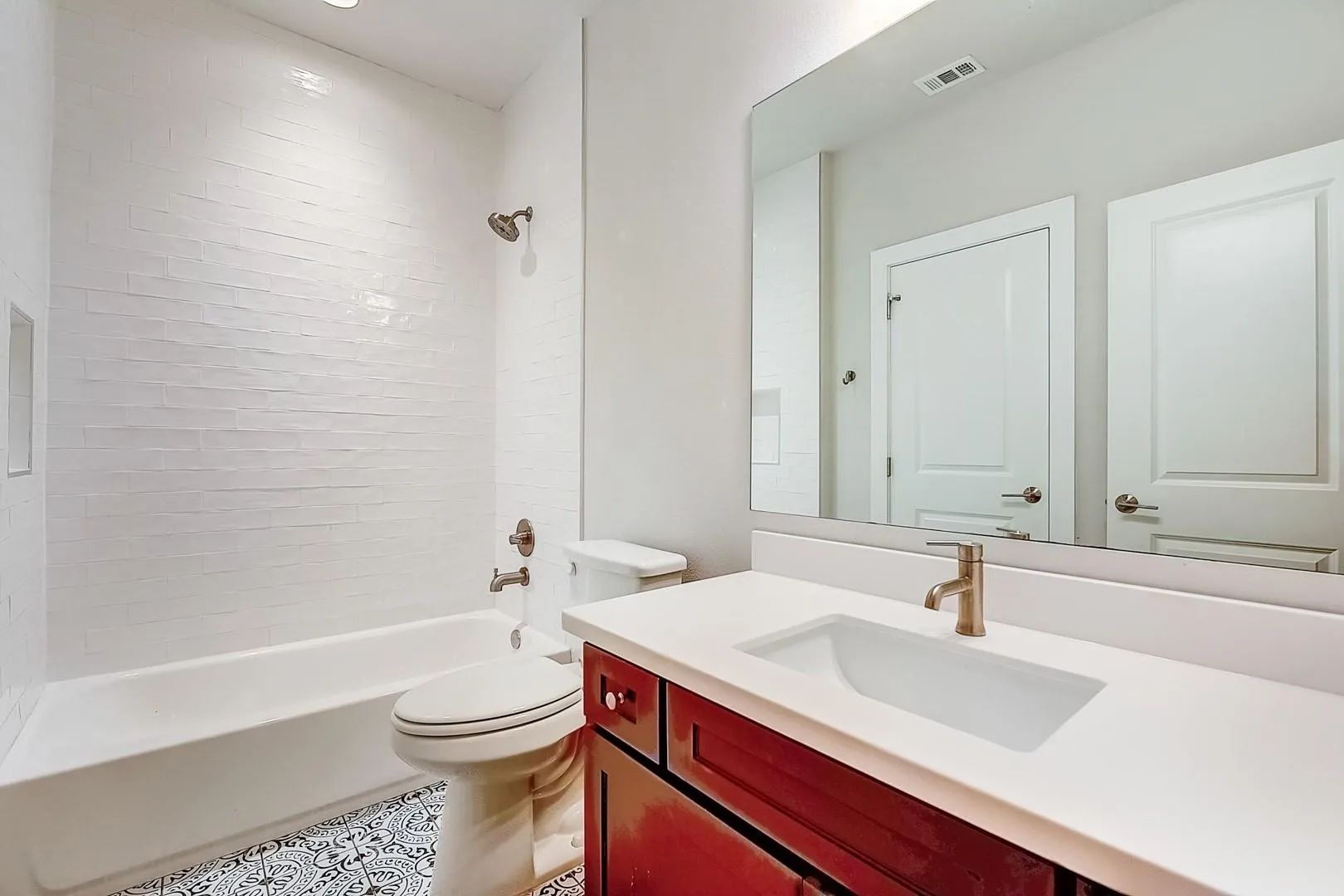 White subway tile bath surround with a built-in niche, vanity with an integrated sink, and bronze finish faucet