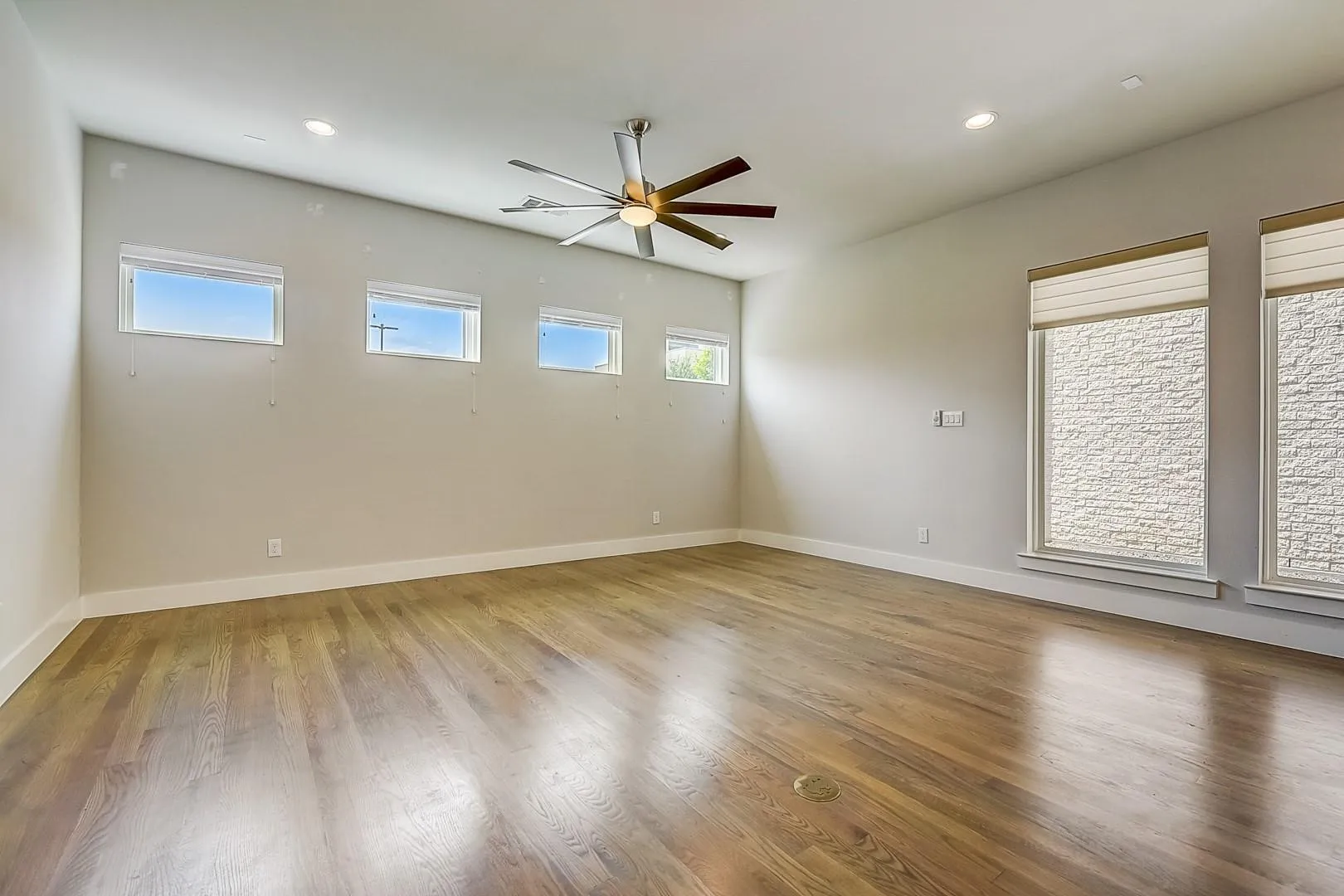 Spacious room featuring wood-finish flooring, recessed lighting, and a modern ceiling fan
