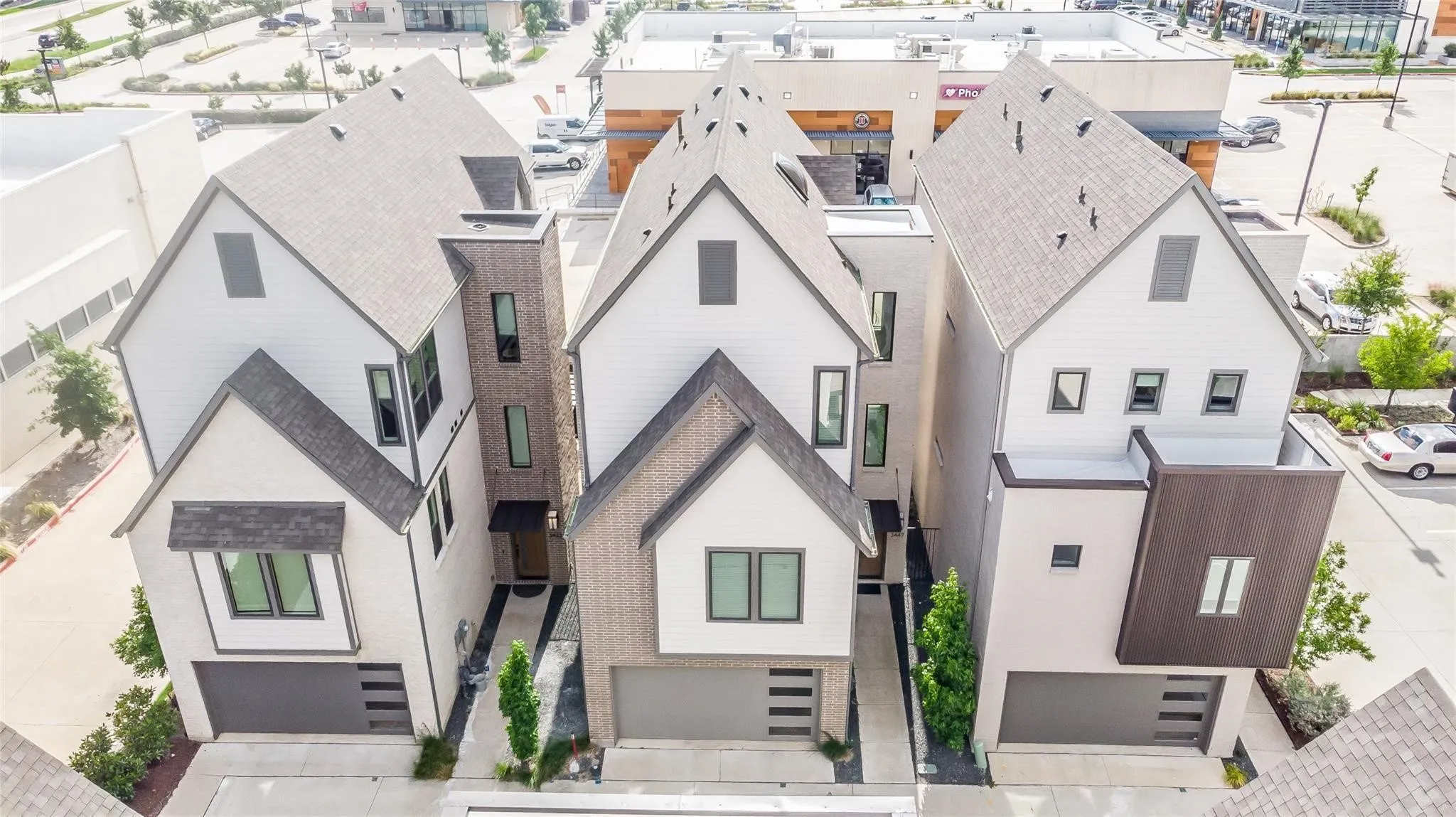 Contemporary townhome with a multi-textured facade, featuring a prominent gable roof, dark-framed windows, and an integrated garage