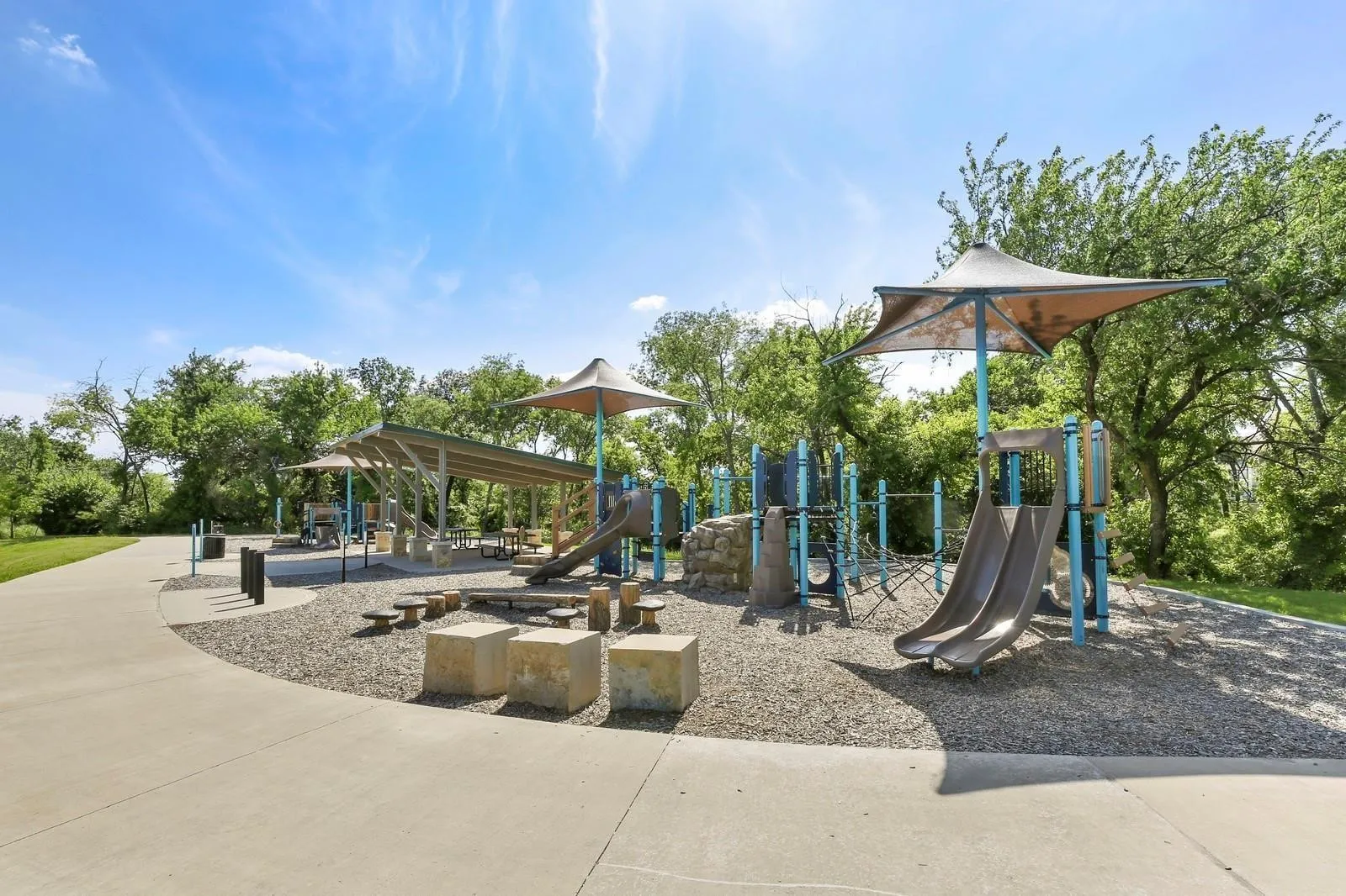 Playground area featuring multiple slides, climbing structures, and shaded seating areas