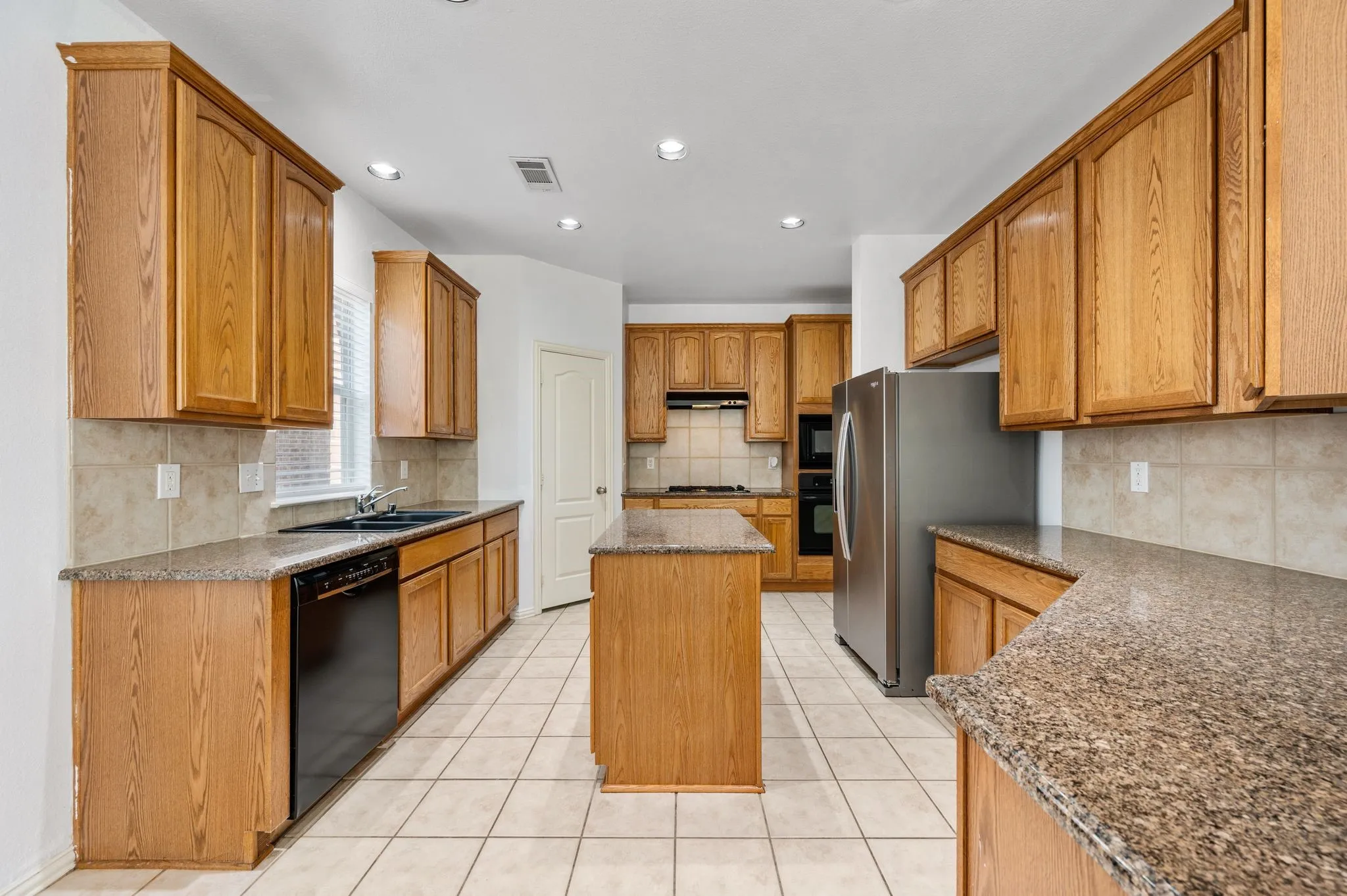 Oversized sink, gas cooktop and stainless steel refrigerator.