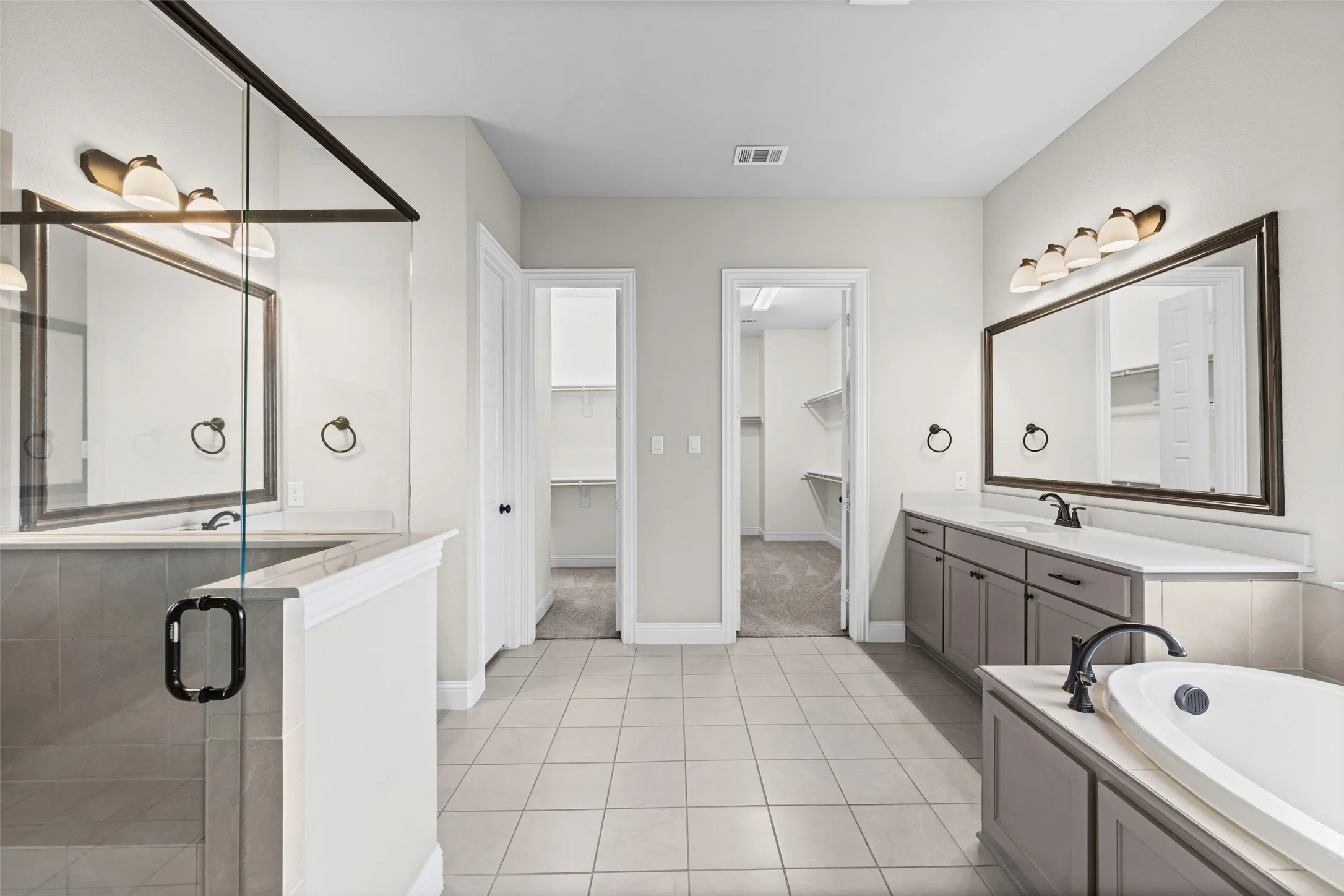 Massive primary bathroom has separate vanities, shower, garden tub, and two huge closets, one that connects to the laundry room