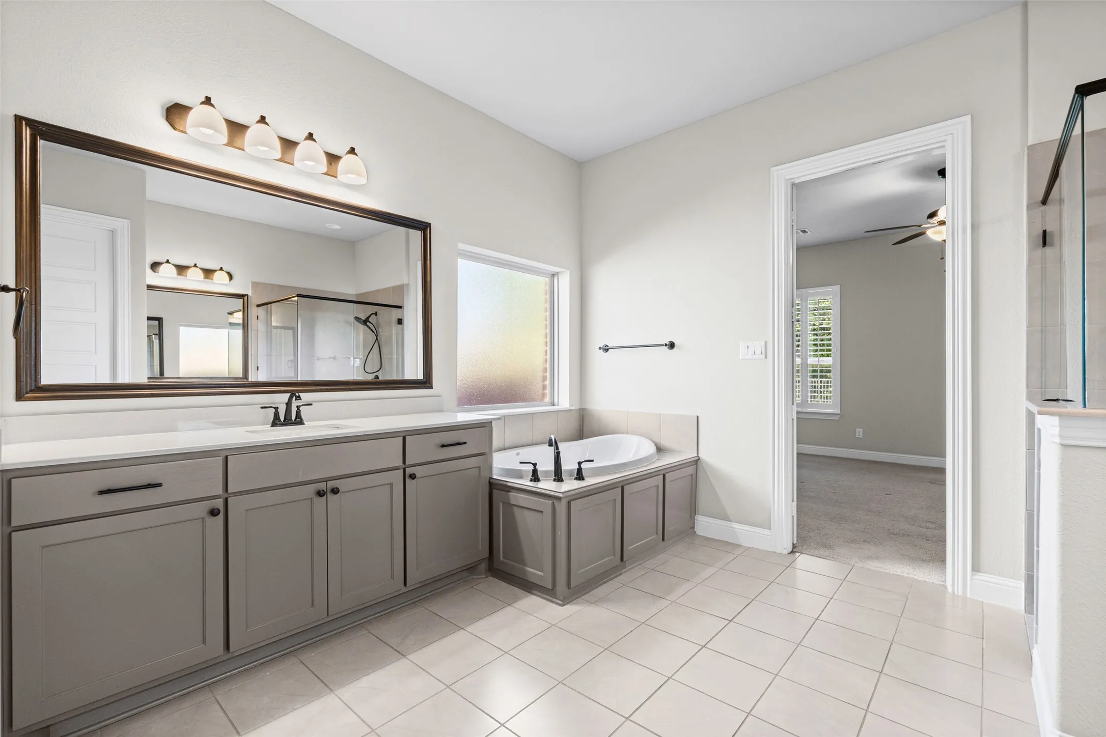 Massive primary bathroom has separate vanities, shower, garden tub, and two huge closets, one that connects to the laundry room
