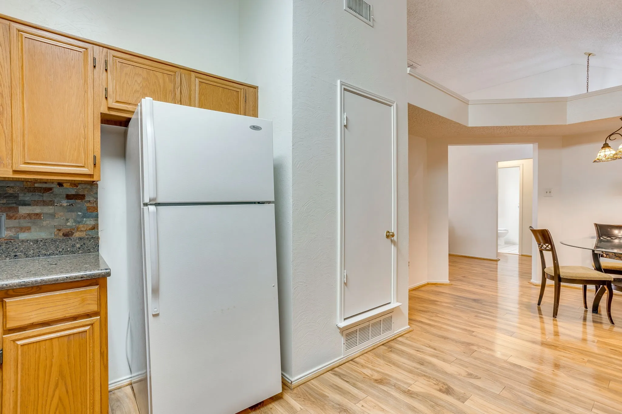Kitchen area featuring wood-finish cabinetry, stone backsplash, and a built-in pantry