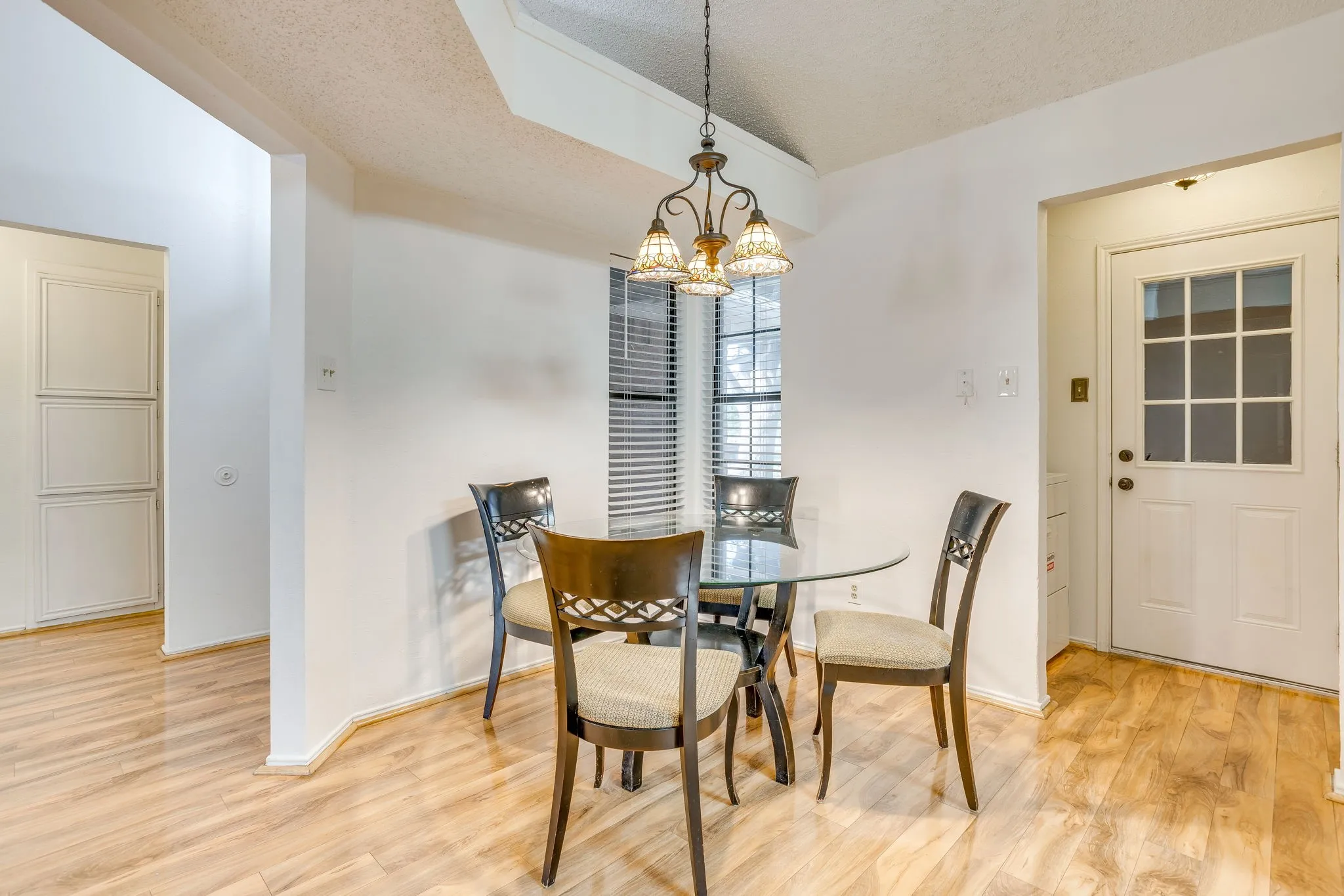 Wood-finish flooring throughout, with a built-in storage cabinet and a paneled door featuring a window grid