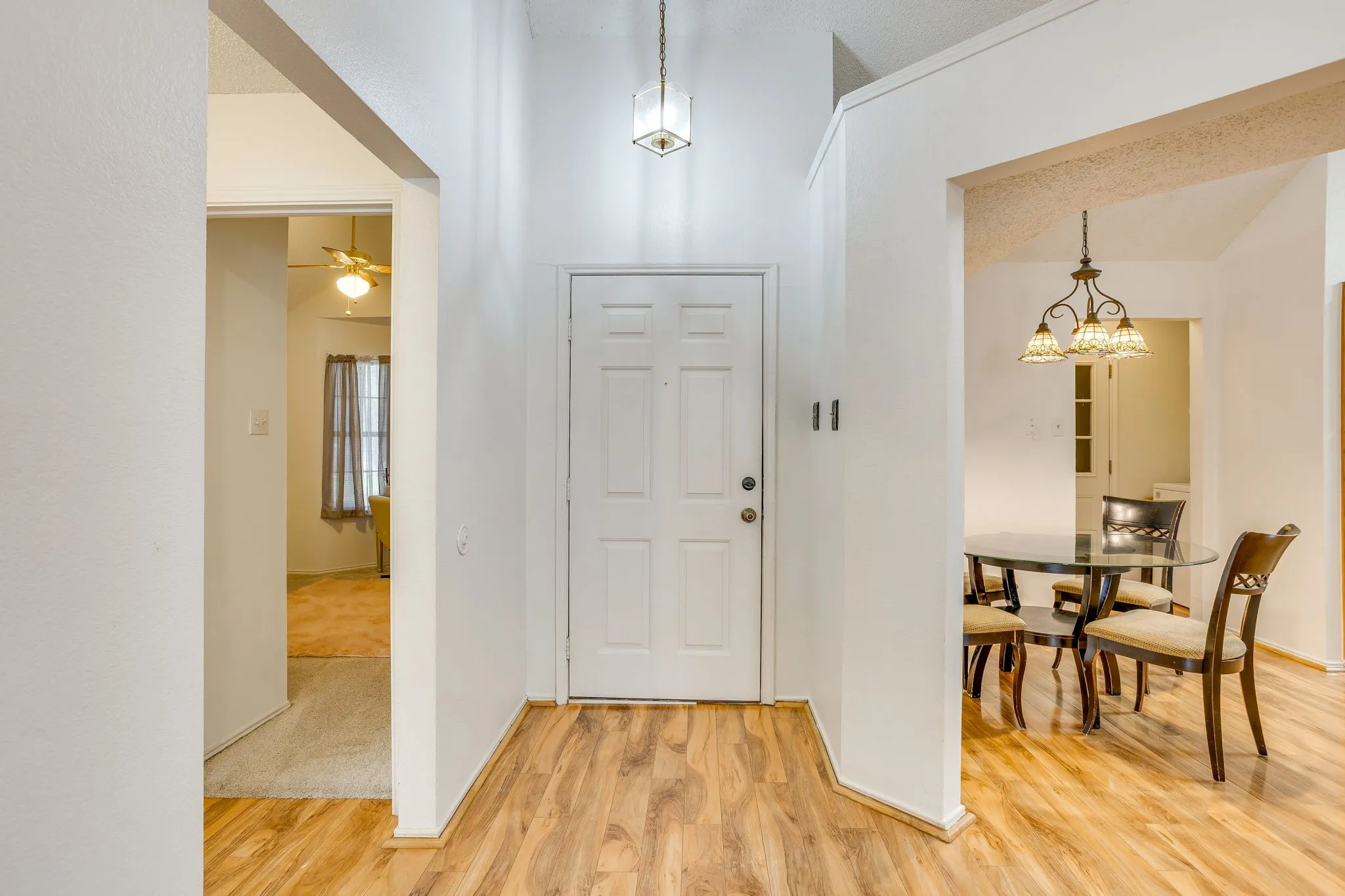 Entry with wood-finish flooring, vaulted ceiling, and decorative pendant light fixture