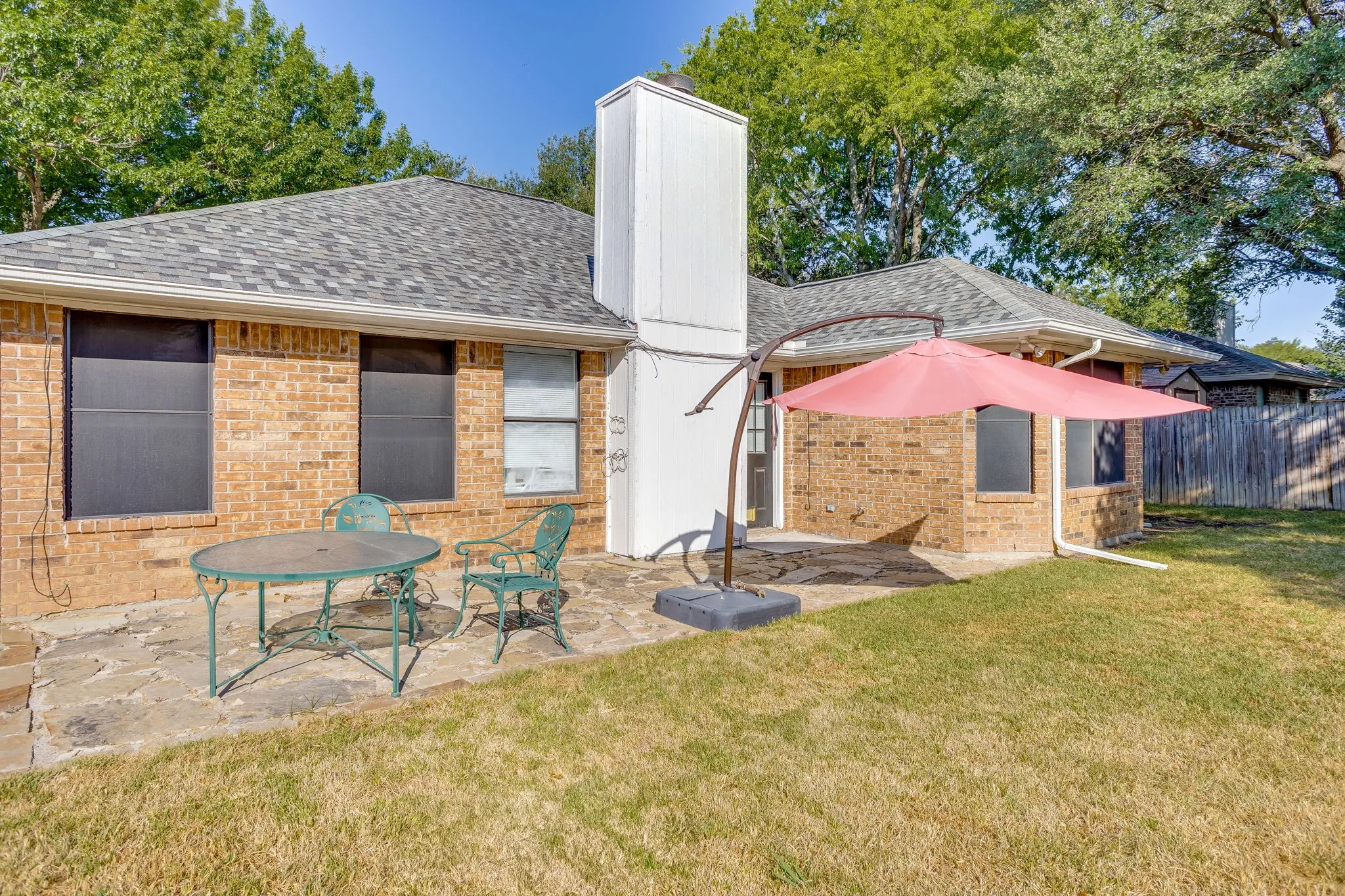 Brick exterior with a shingle roof and a stone patio