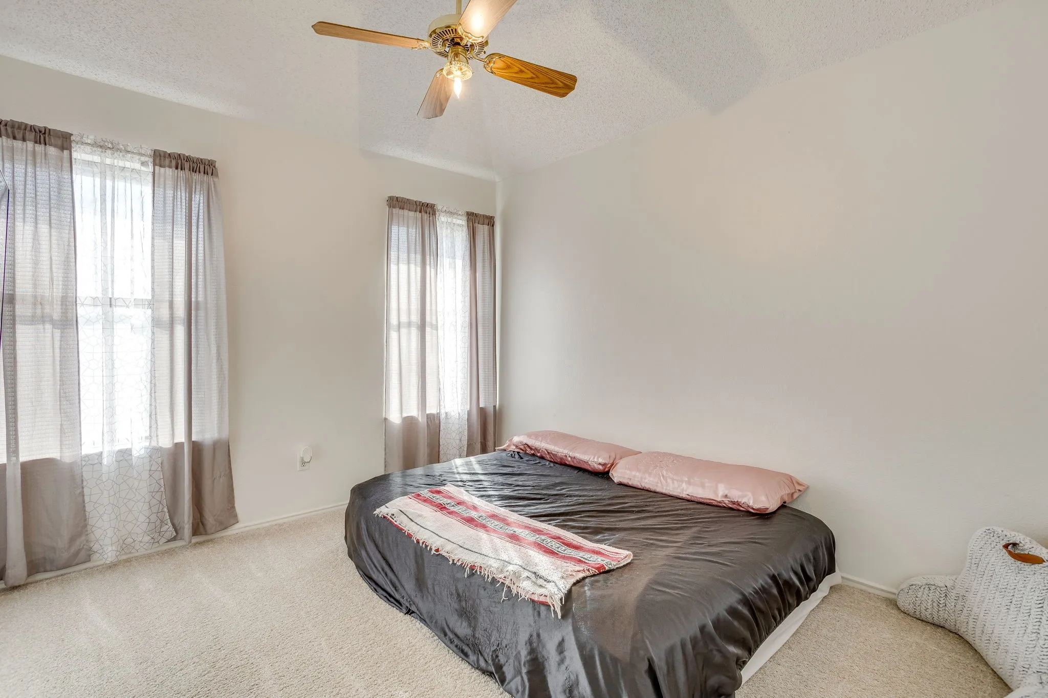 Bright secondary bedroom #3 featuring dual windows with sheer and lined drapery, ceiling fan with brass finish, and neutral carpeting throughout