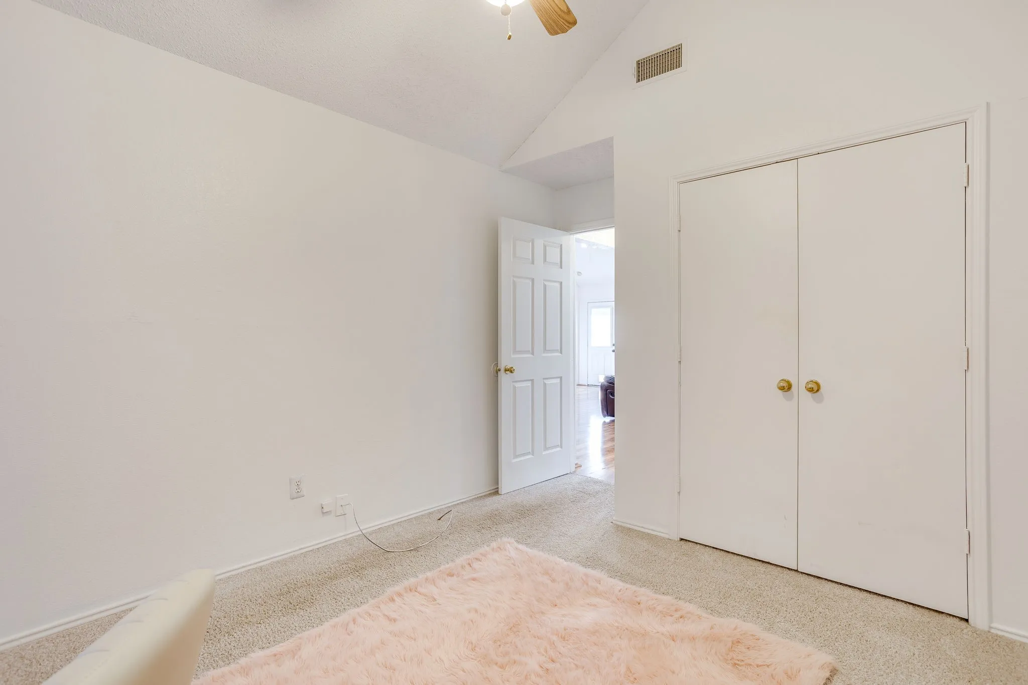 Bright secondary bedroom #2 featuring neutral carpeting, dual closets with brass hardware, and clean white finishes throughout