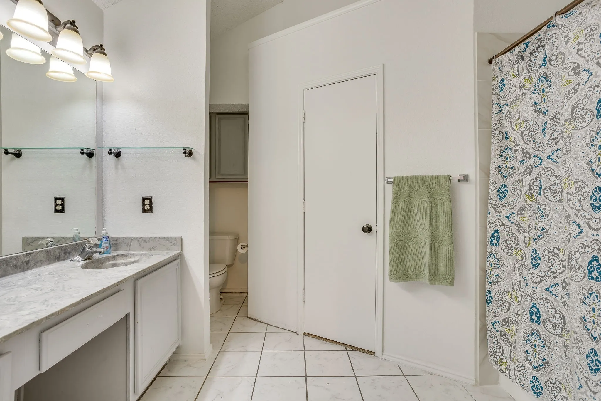 Spa-inspired primary bathroom featuring dual vanities with marble-look countertops, recessed lighting, and polished chrome fixtures
