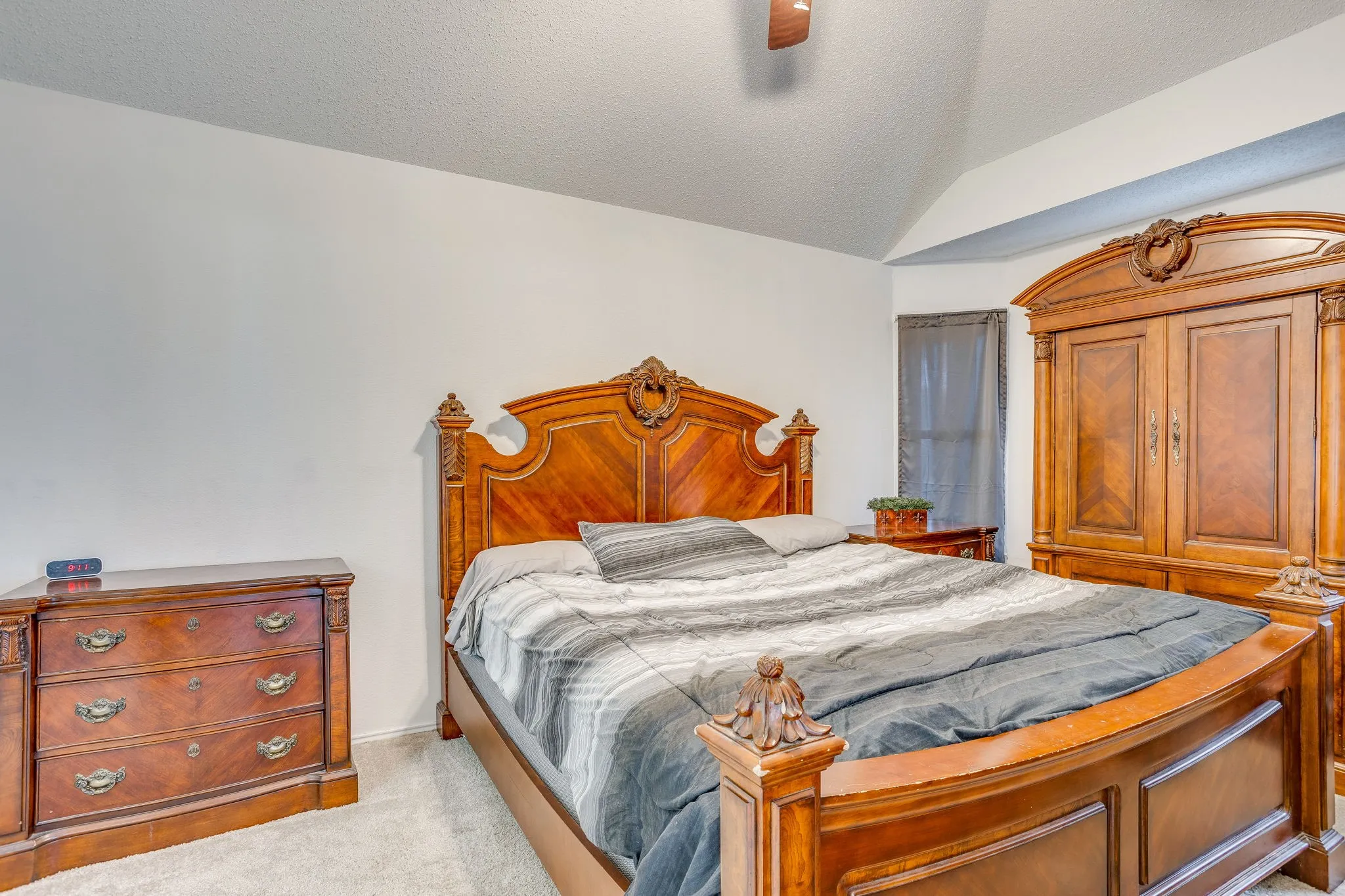 Vaulted ceiling with ceiling fan, light-colored carpet flooring, and neutral wall paint
