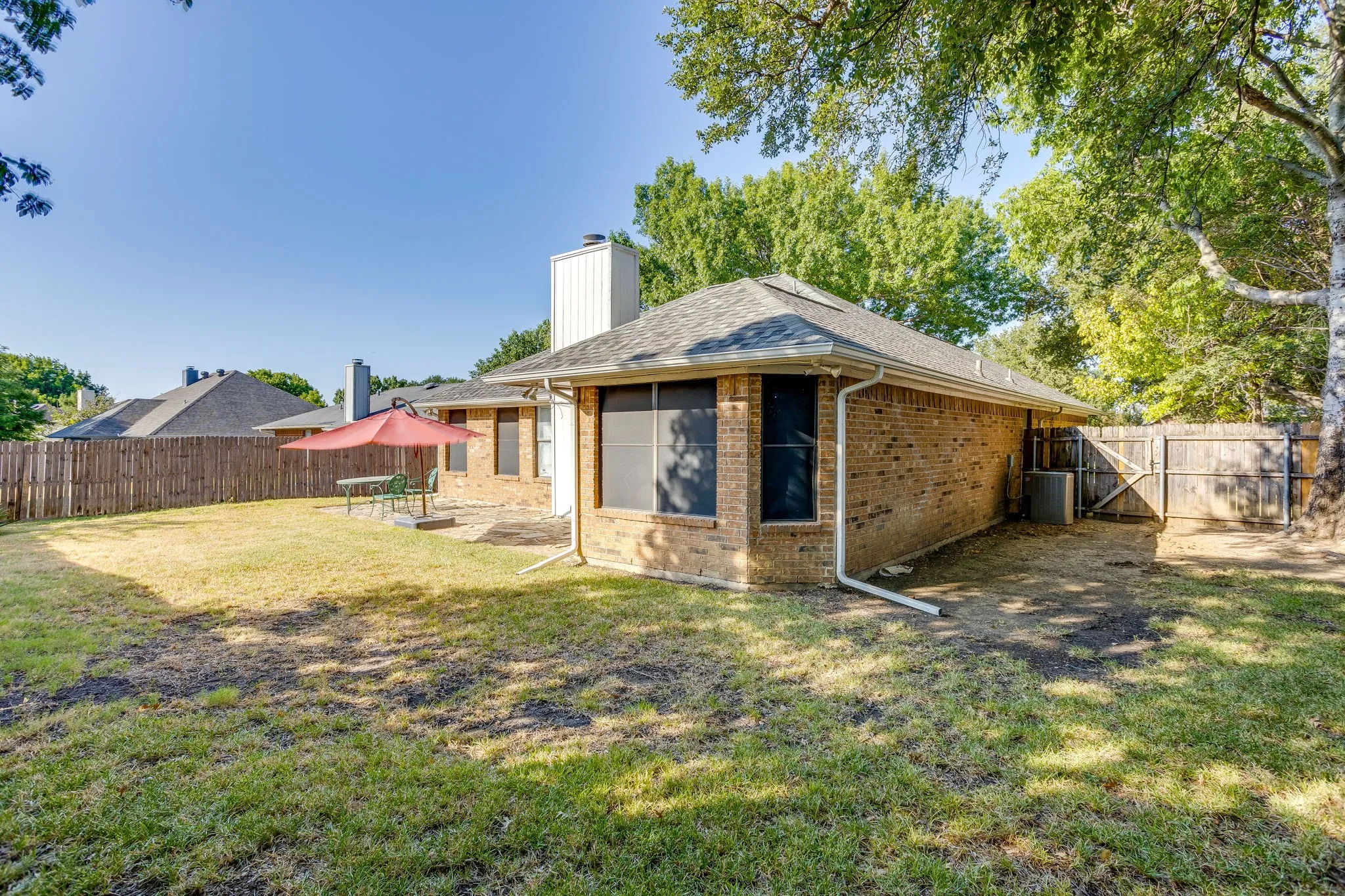 Expansive backyard with a brick exterior, shingle roof, and a privacy fence