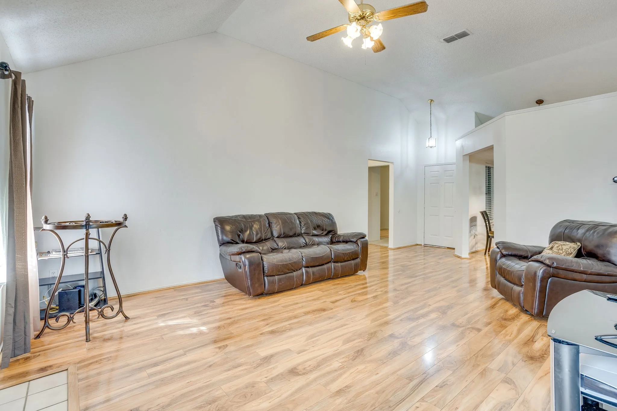 Vaulted ceilings, wood-finish flooring, ceiling fan, and white walls