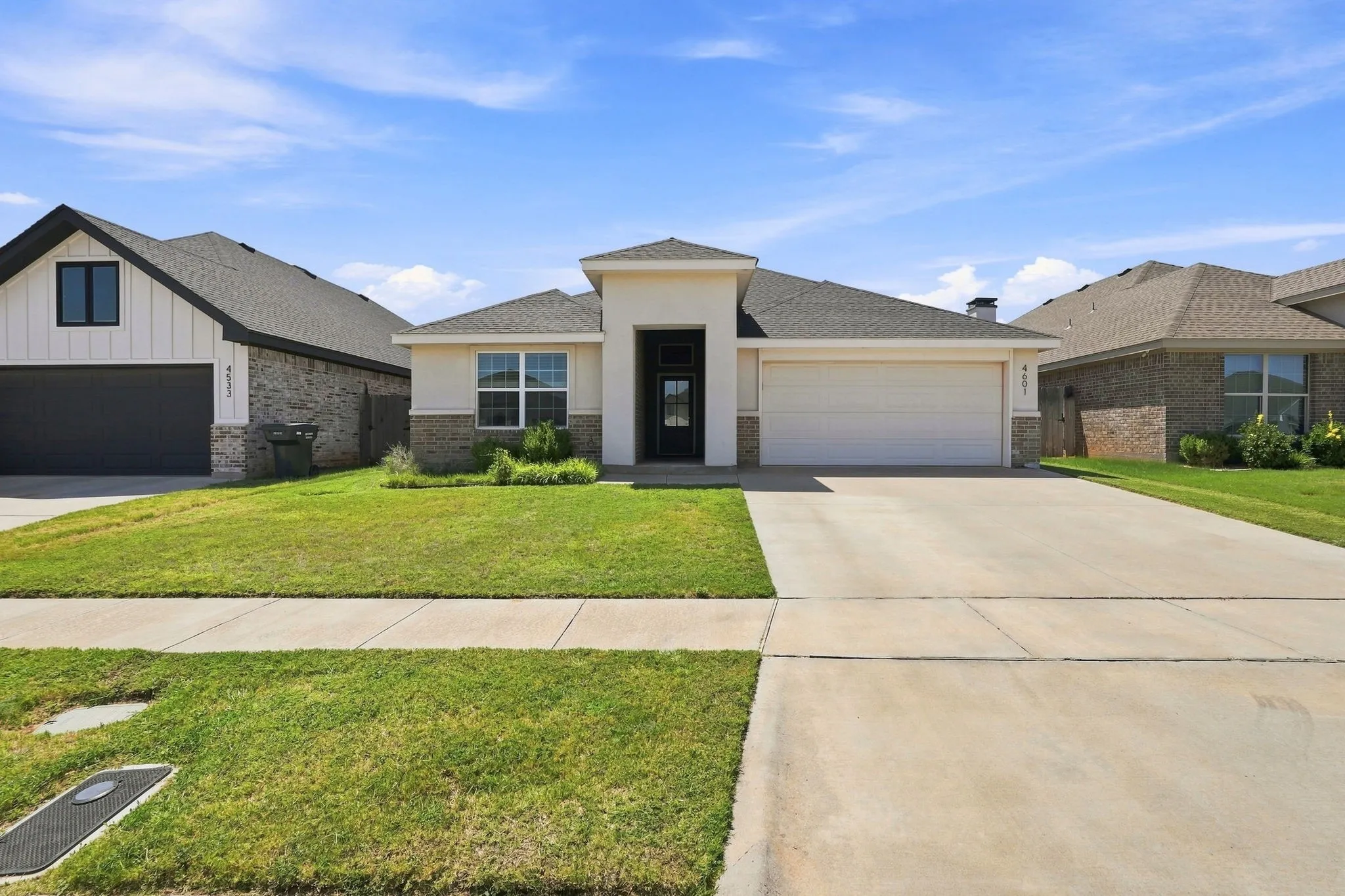 Contemporary exterior with stucco and stone veneer, a covered entry, an attached garage, and a concrete driveway