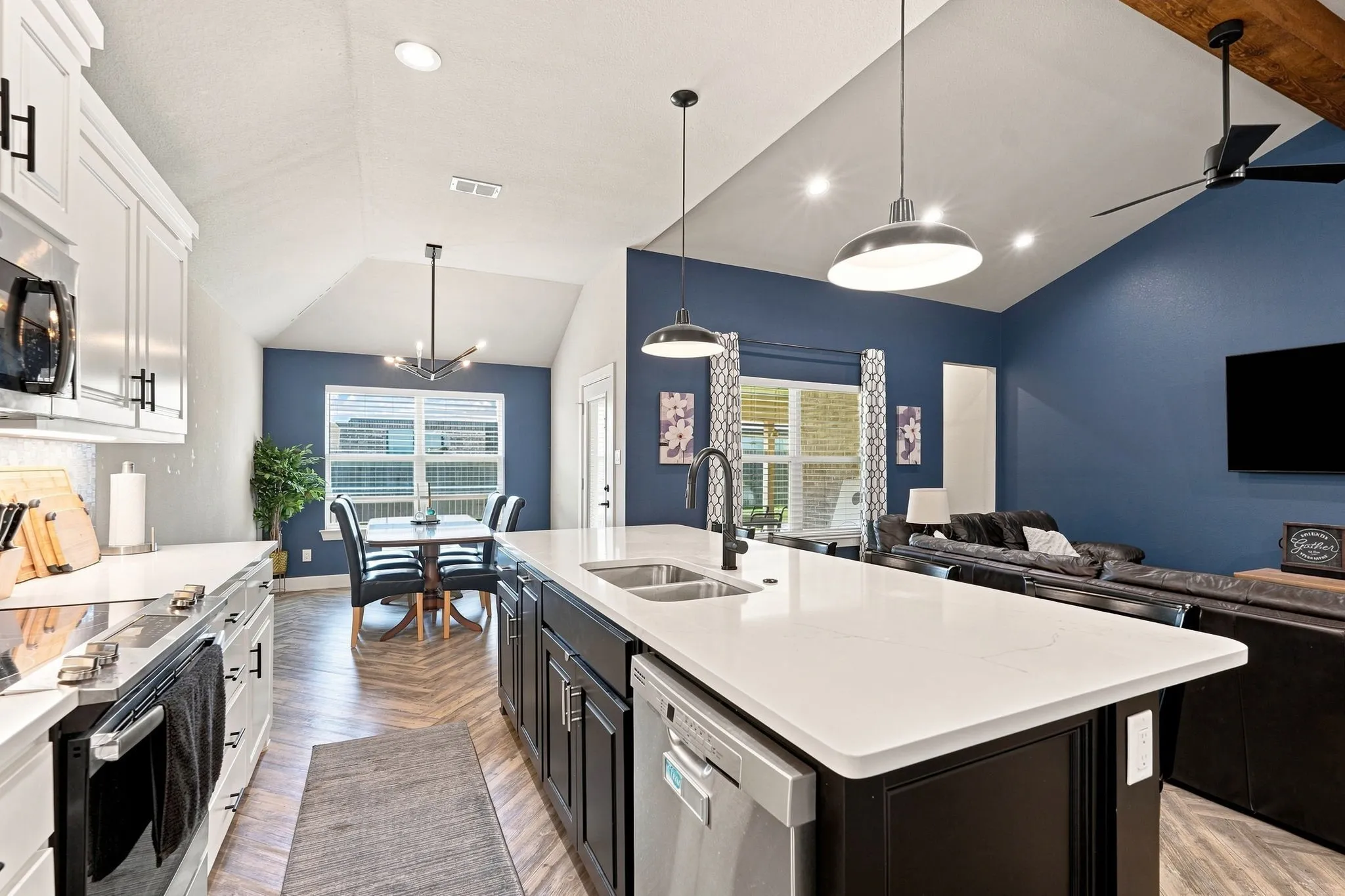 Open-concept living area with vaulted ceilings, a central kitchen island with seating, dark wood-finish cabinetry, and stainless steel appliances
