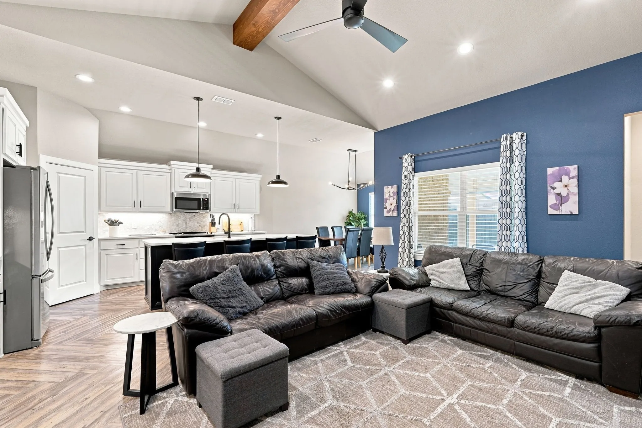 Vaulted ceiling with exposed wood beam, recessed lighting, and ceiling fan