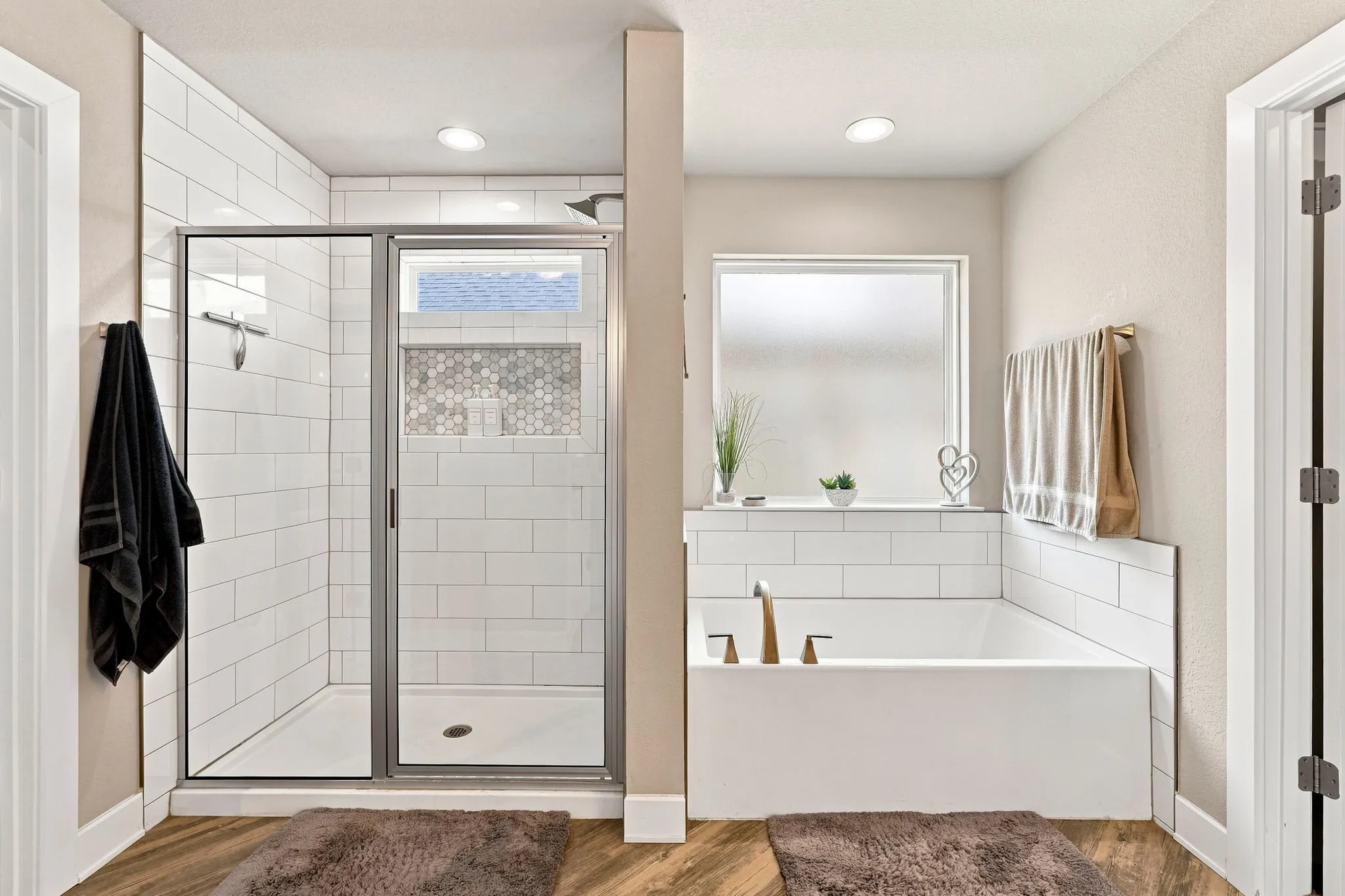 Walk-in shower with clear glass enclosure, white subway tile surround, and hexagonal tile accent niche
