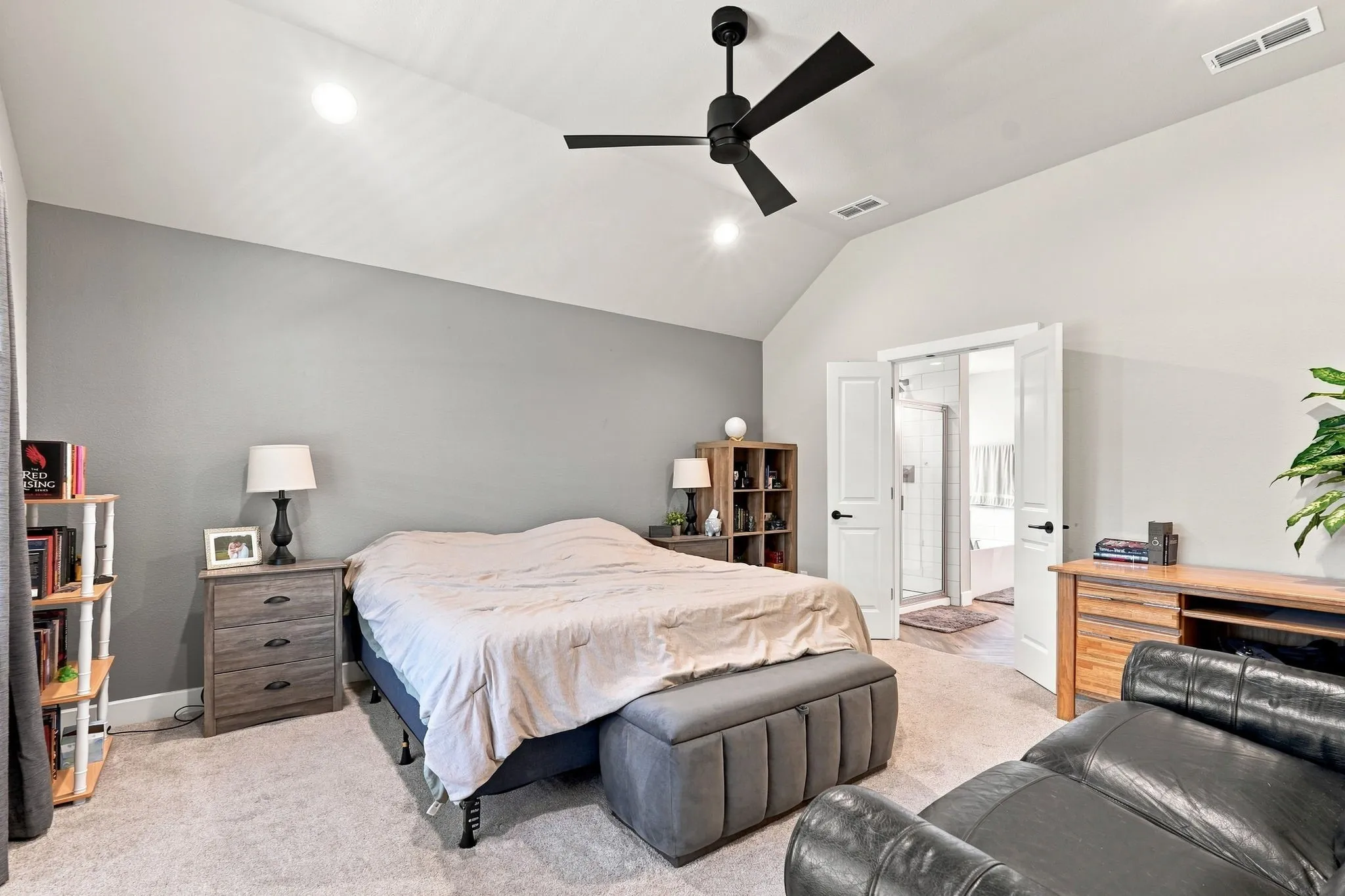 Vaulted ceiling with a black ceiling fan, light-toned carpeting, and a two-toned paint scheme