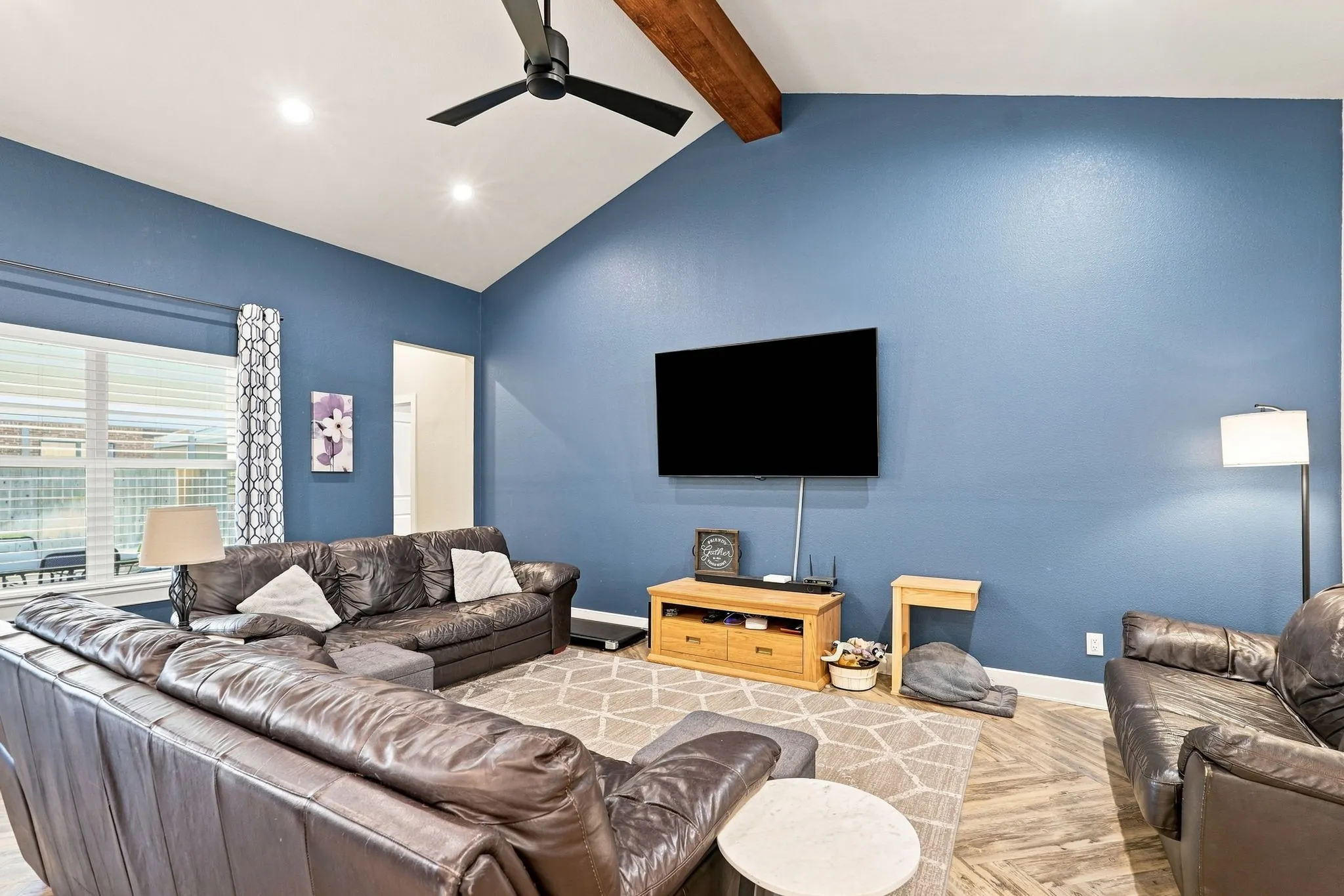 Vaulted ceiling featuring a dark wood beam and a ceiling fan