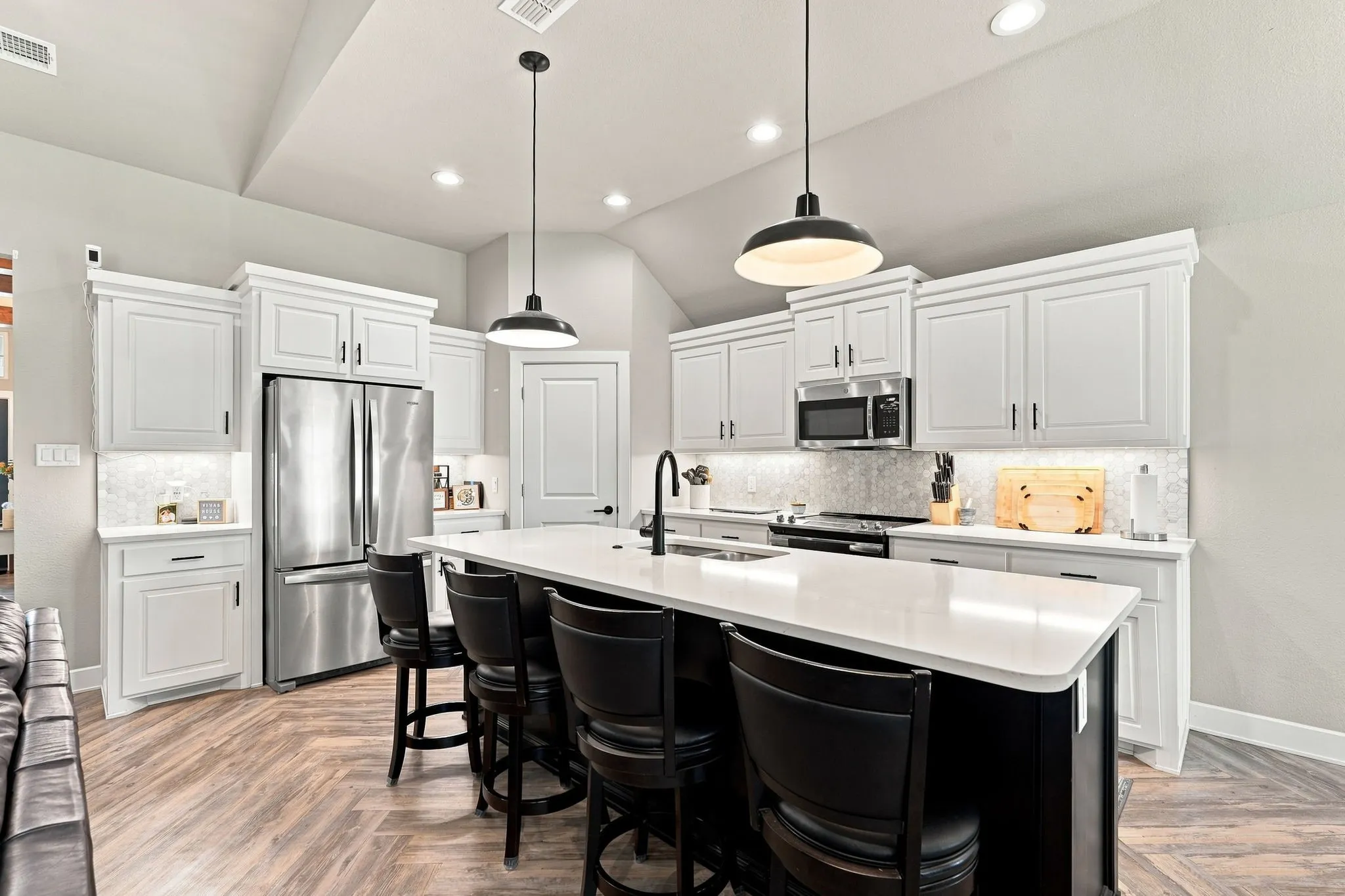 Kitchen featuring a spacious island, white cabinetry, integrated stainless steel appliances, and wood-finish flooring