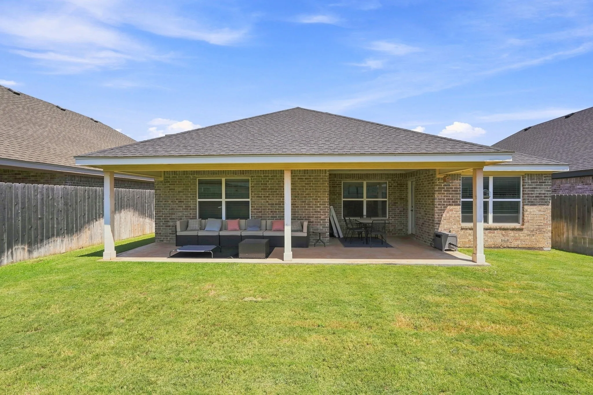Expansive backyard featuring a covered patio, a manicured lawn, and privacy fencing