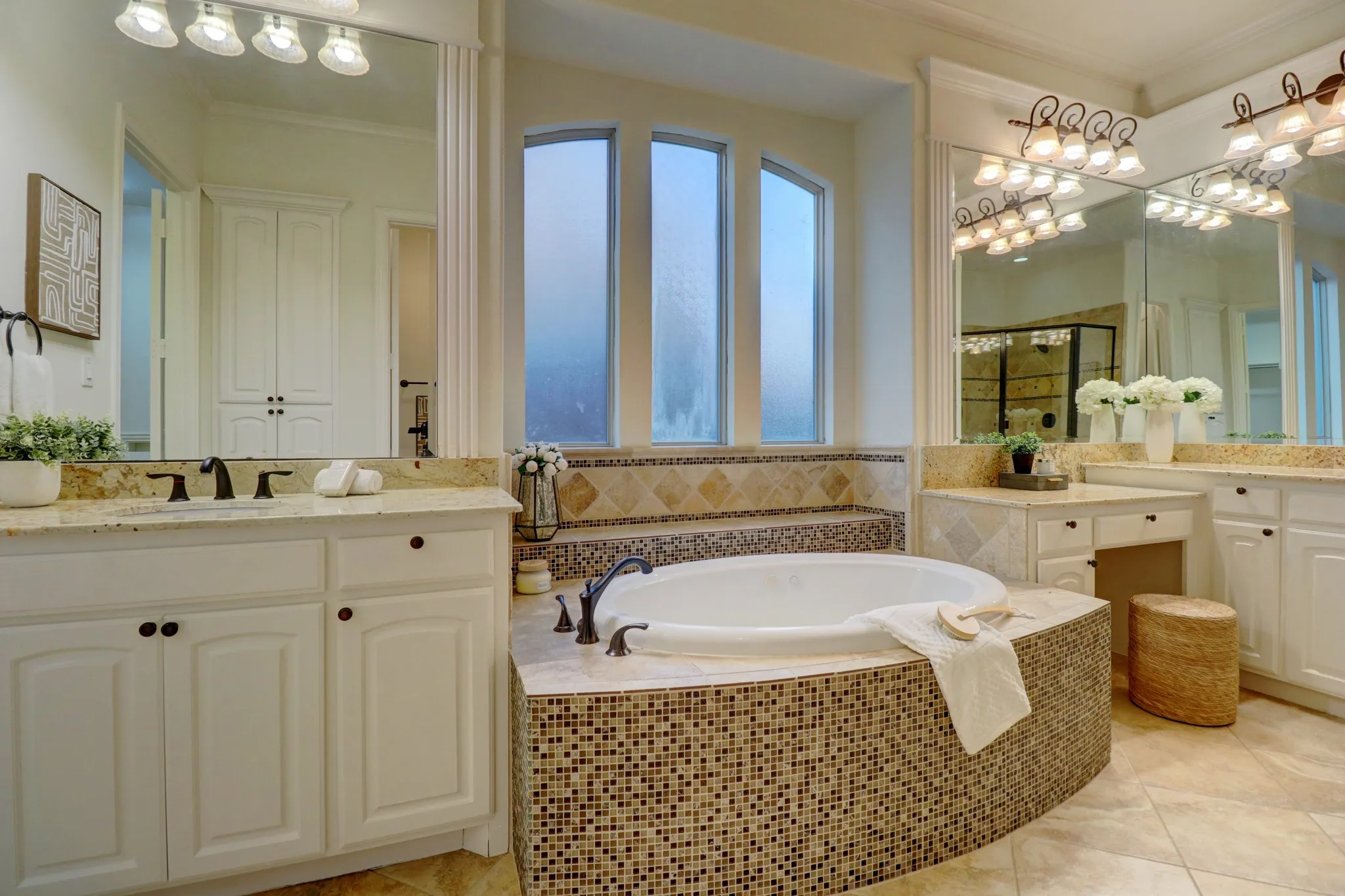Dual vanity with integrated sinks and granite countertops, a built-in soaking tub with mosaic tile surround, and a separate vanity area