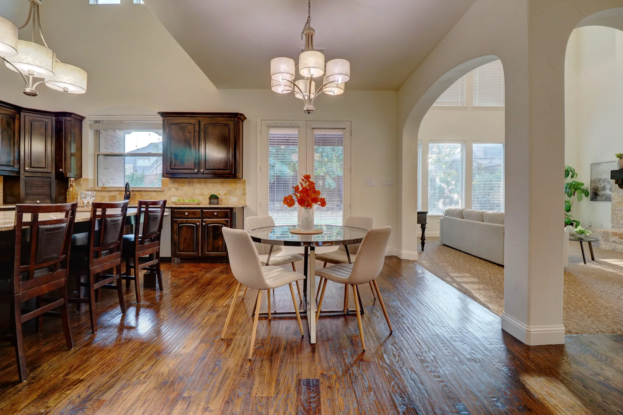 Hardwood flooring, arched doorways, dark wood cabinetry, built-in breakfast bar, and vaulted ceilings