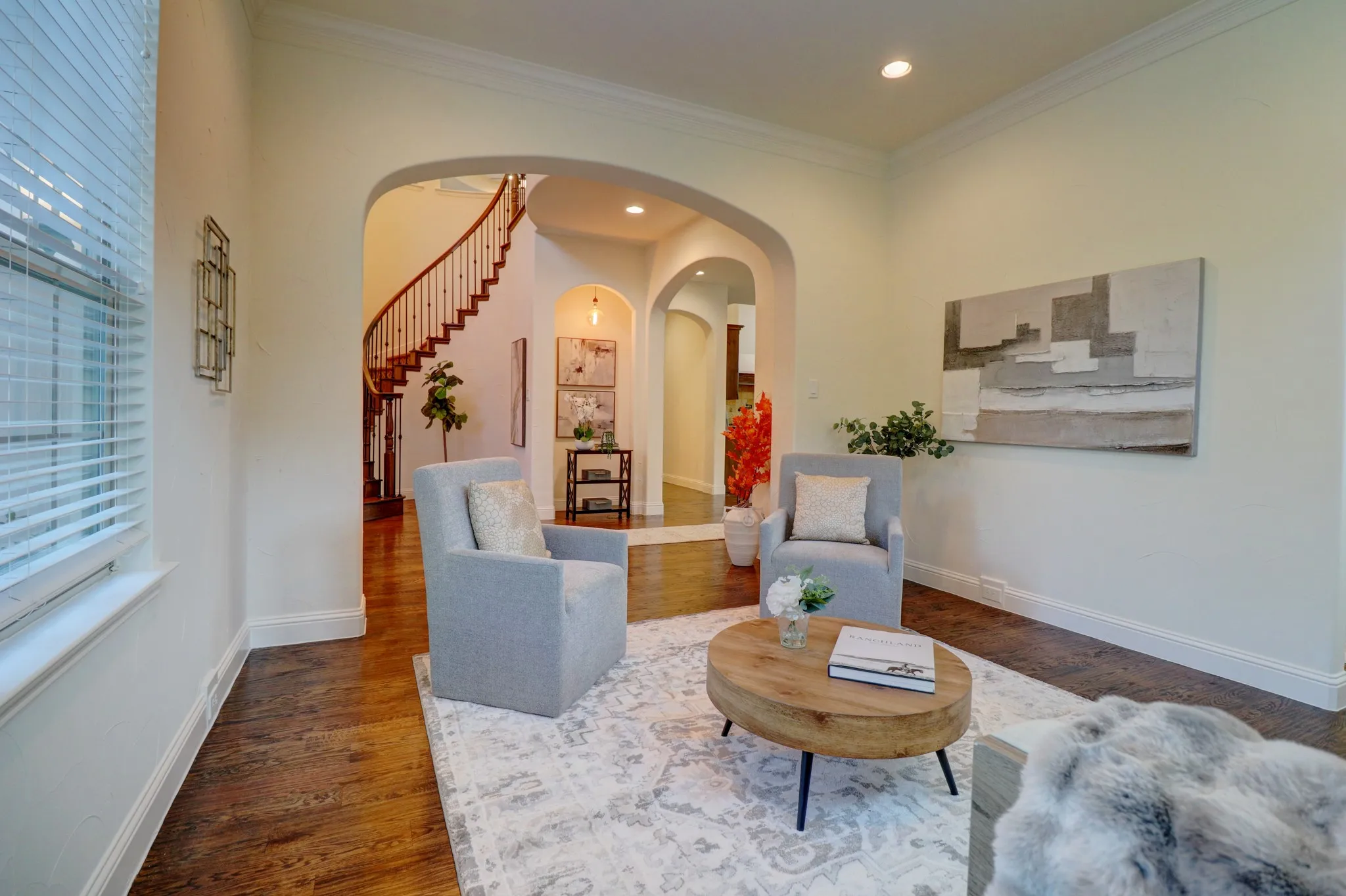 Hardwood-finish flooring, recessed lighting, arched doorways, crown molding, and a visible curved staircase