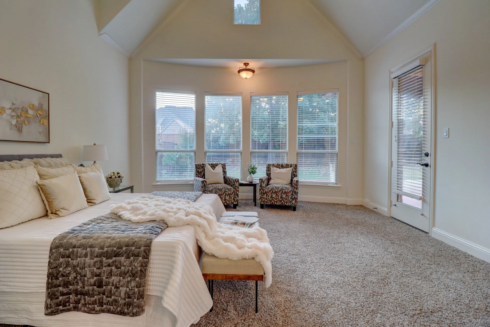 Vaulted ceiling with an upper window, bay window with multiple panes, ceiling-mounted light fixture, and a glass-paneled door