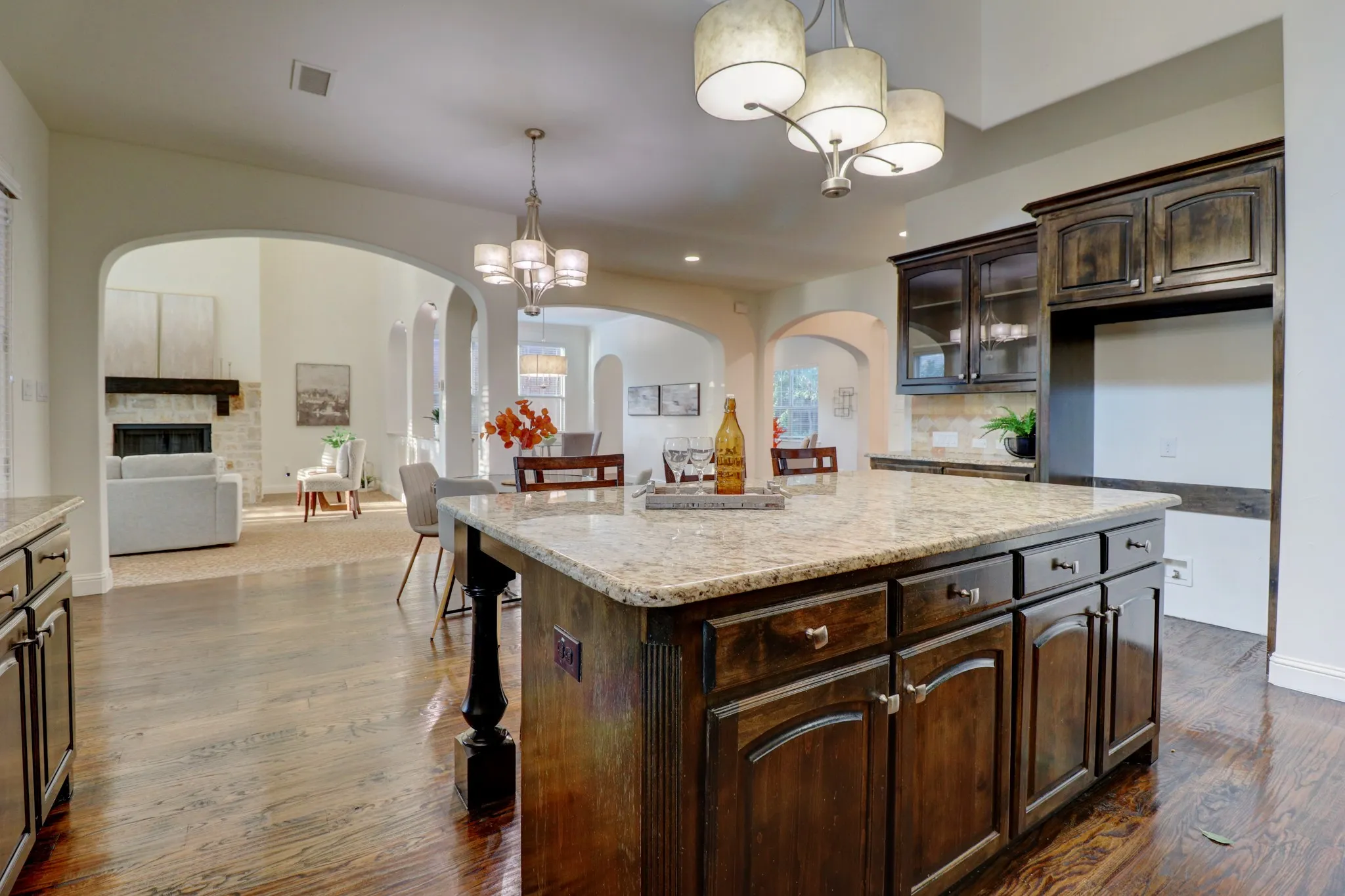 Kitchen island with a light-toned countertop, dark wood-finish cabinetry, and a ceiling-mounted light fixture