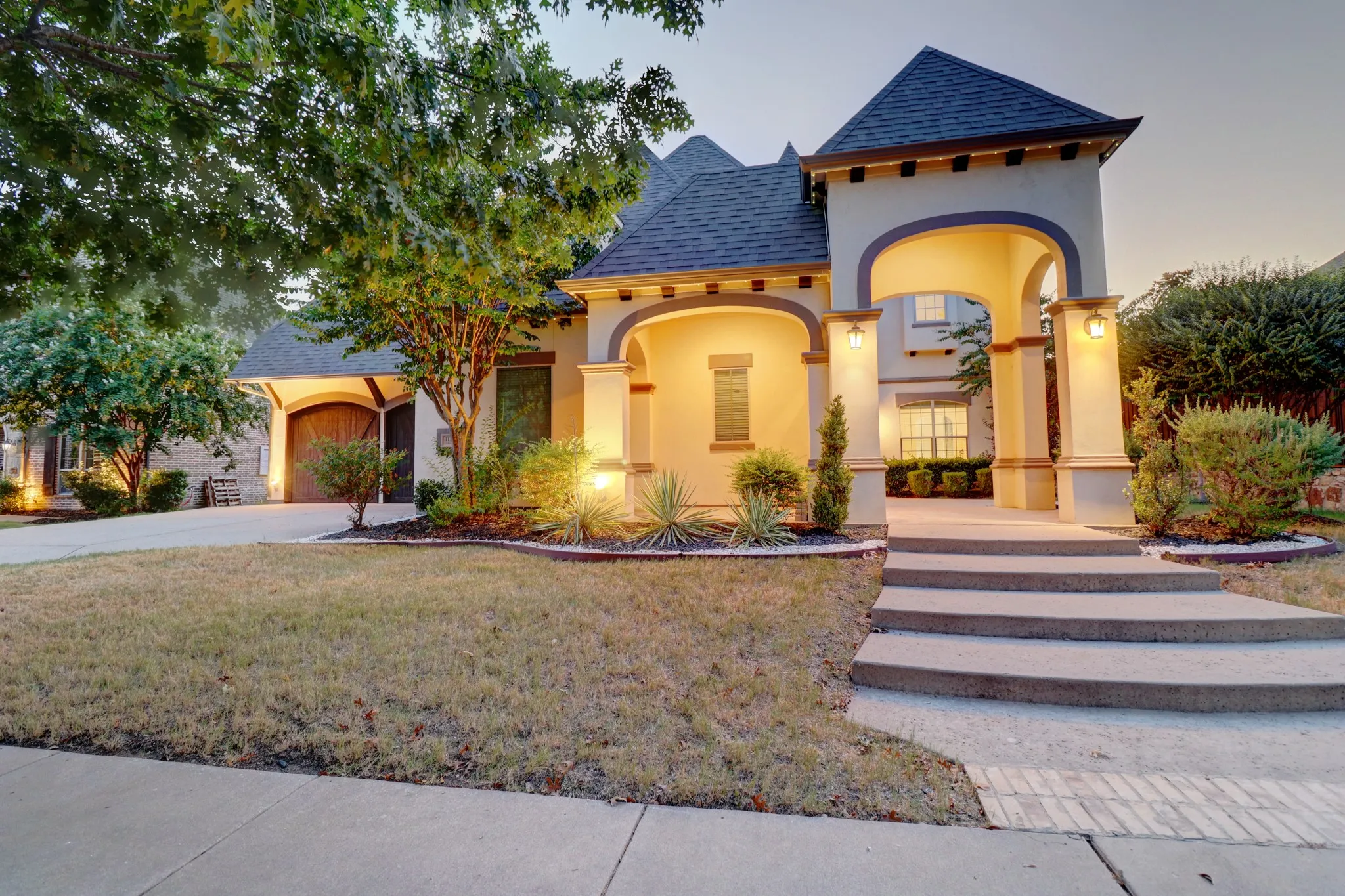 Stucco exterior with arched entry, multi-level concrete steps, and a side-entry garage with a wood-finish door