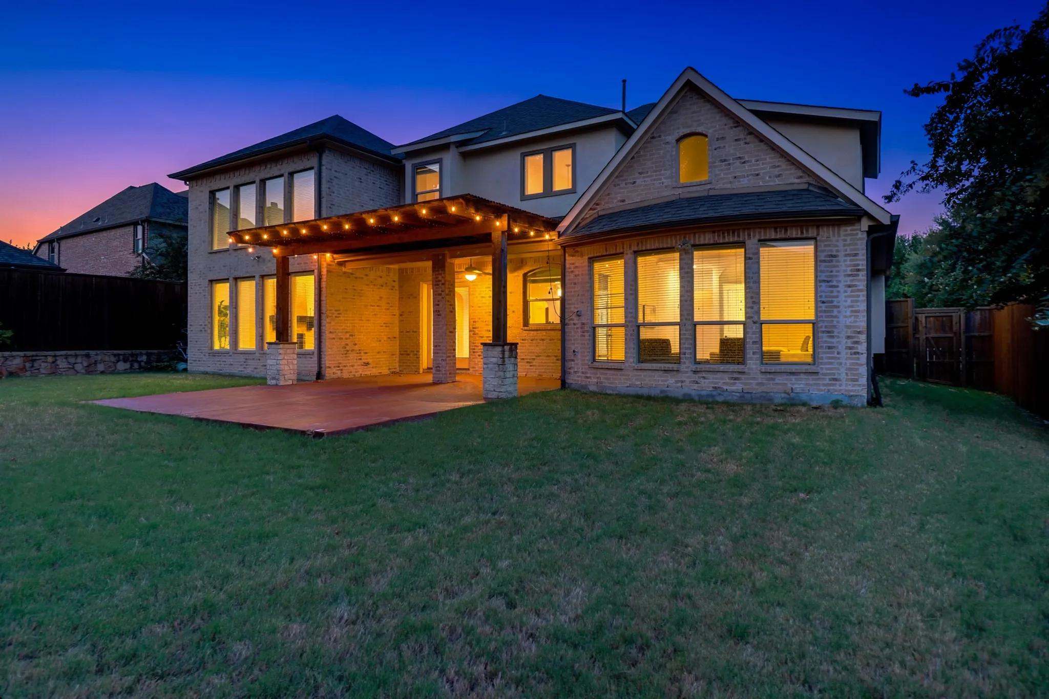 Expansive backyard featuring a manicured lawn, an outdoor patio, and a covered pergola