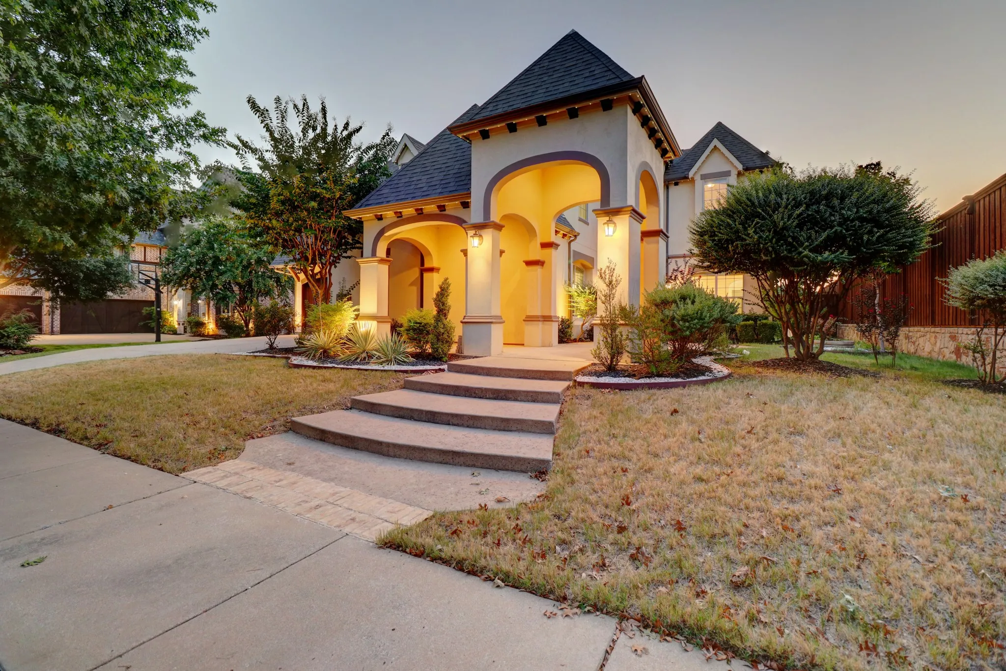 Stucco exterior with arched entry, tiled roof, and concrete steps