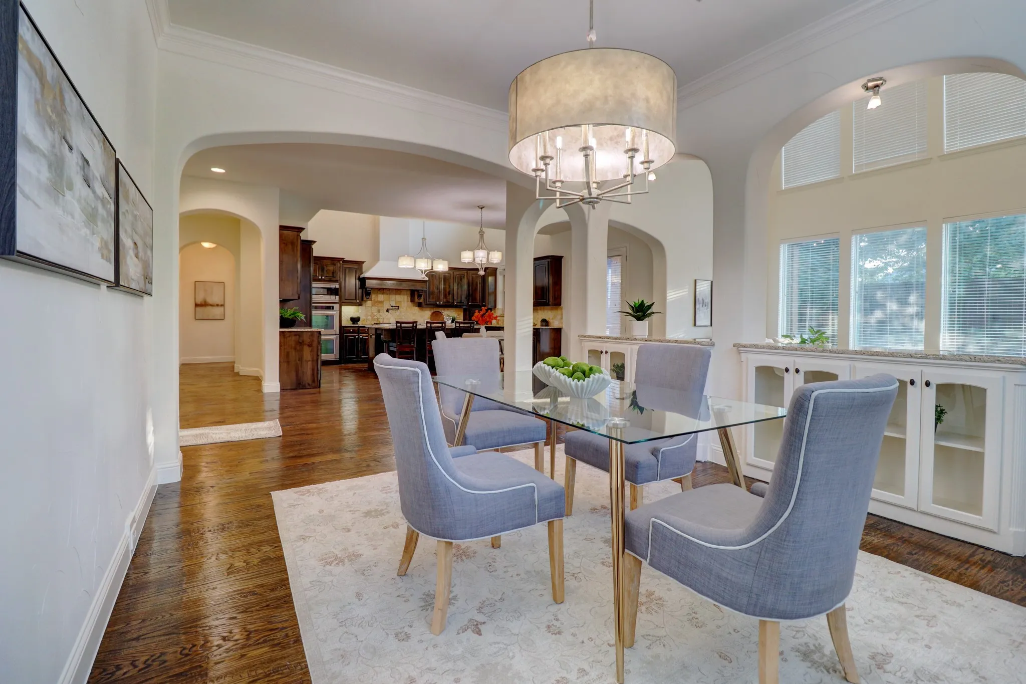 Hardwood flooring, arched doorways, built-in cabinetry with glass inserts, chandelier, and transom windows