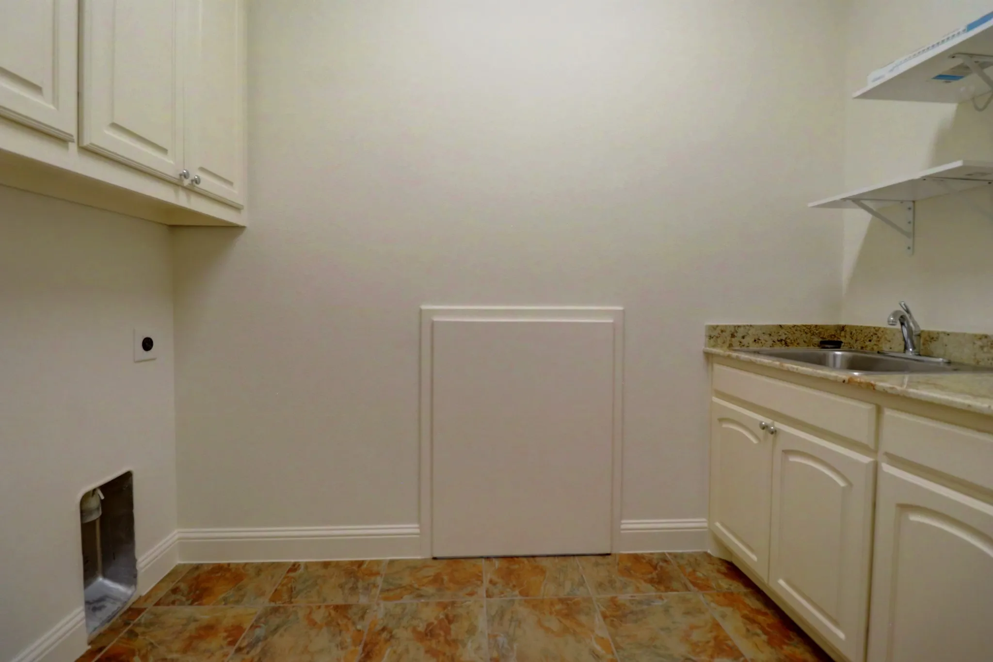 Utility space featuring upper and lower cabinetry, a stainless steel sink, and a stone-finish countertop