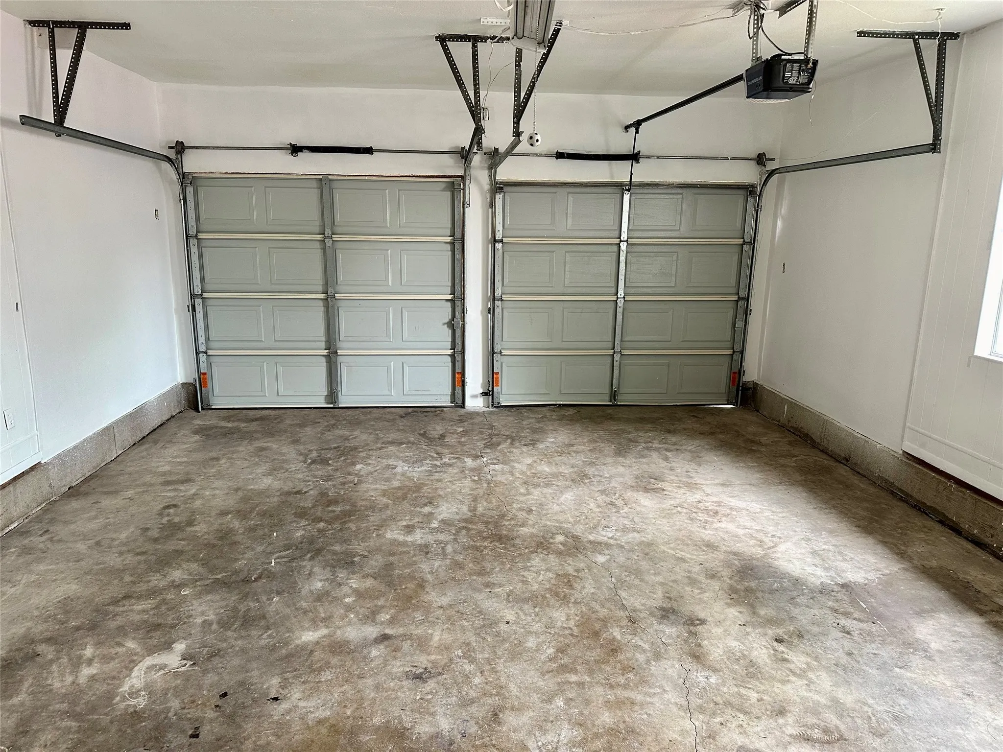 Two-car garage featuring a concrete floor, two individual garage doors, and an automatic garage door opener system