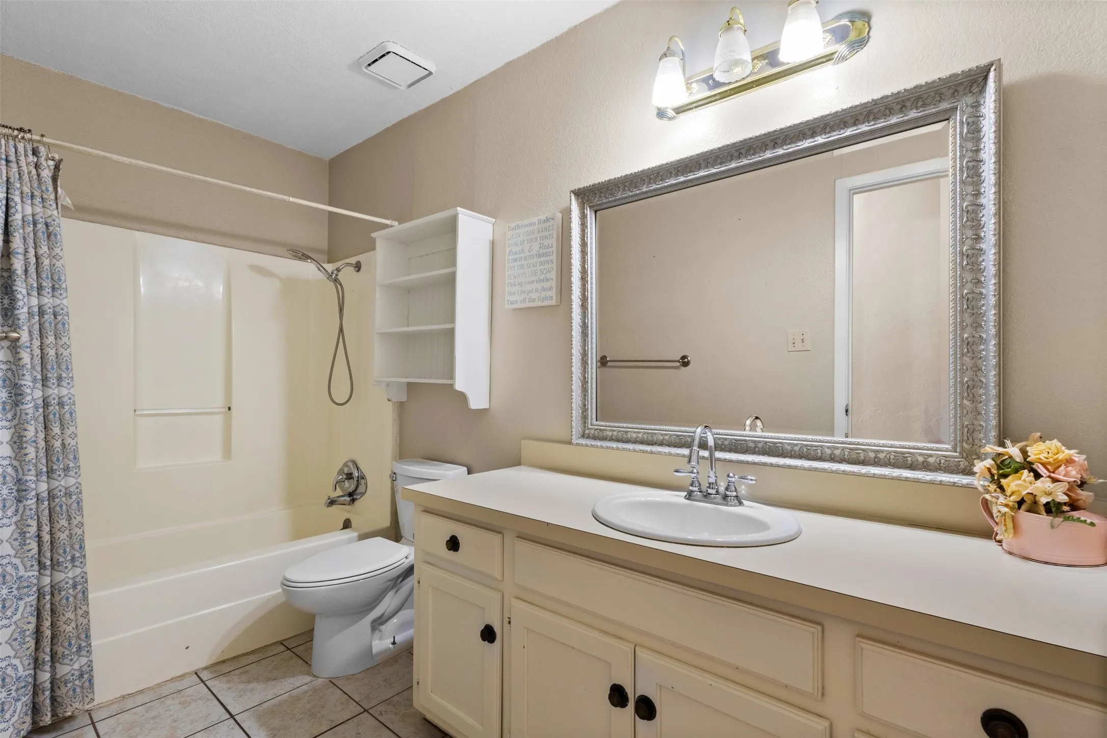 White vanity with double-door cabinetry, built-in oval sink, and a large framed mirror