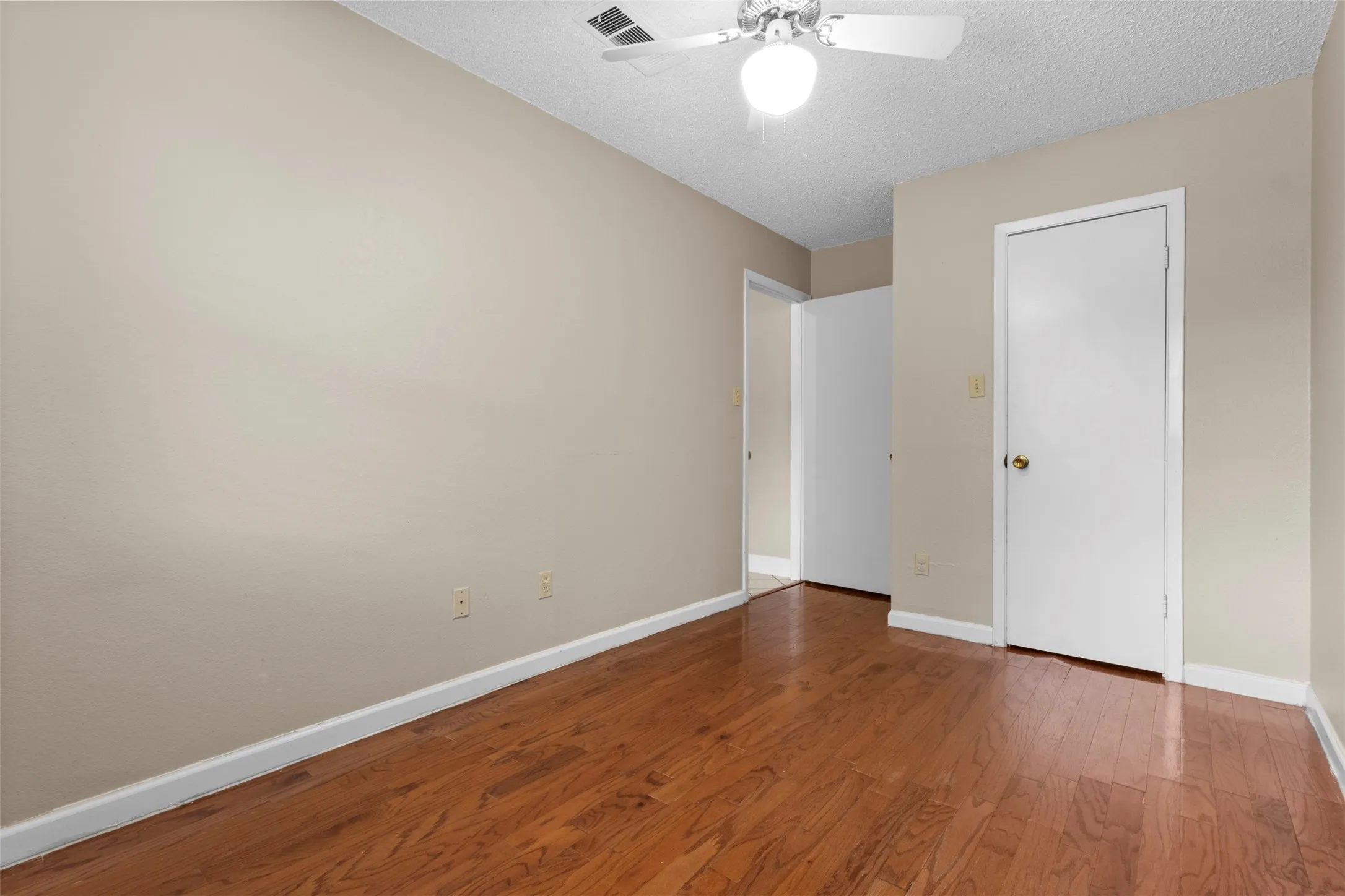 Hardwood-style flooring throughout with neutral wall paint, white trim, and a ceiling fan with integrated lighting
