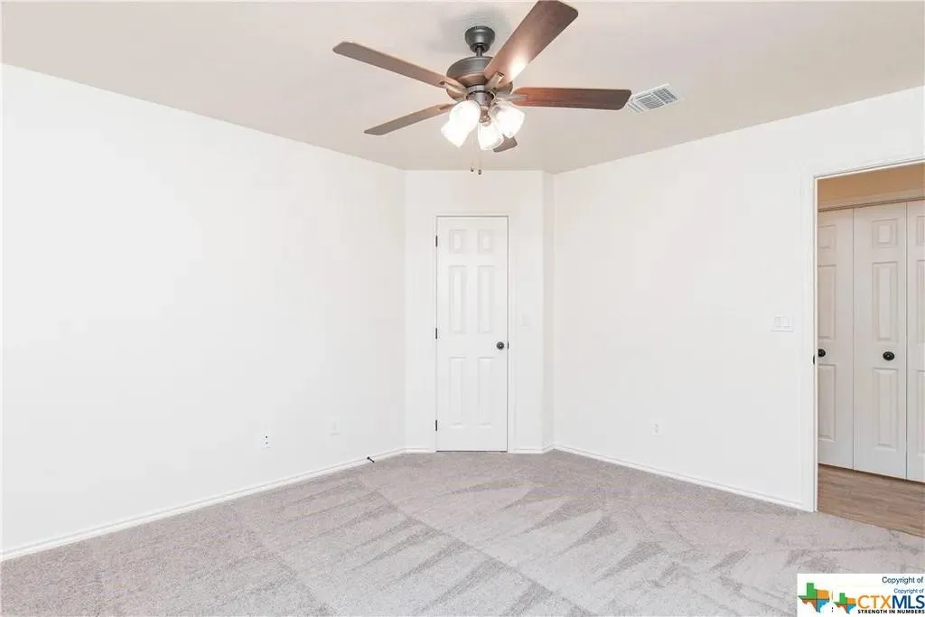 Spacious interior room featuring light-colored walls and patterned carpet flooring