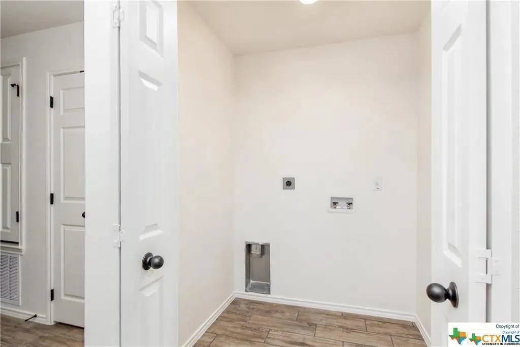Dedicated utility space featuring wood-finish flooring, white walls, and multiple panel doors