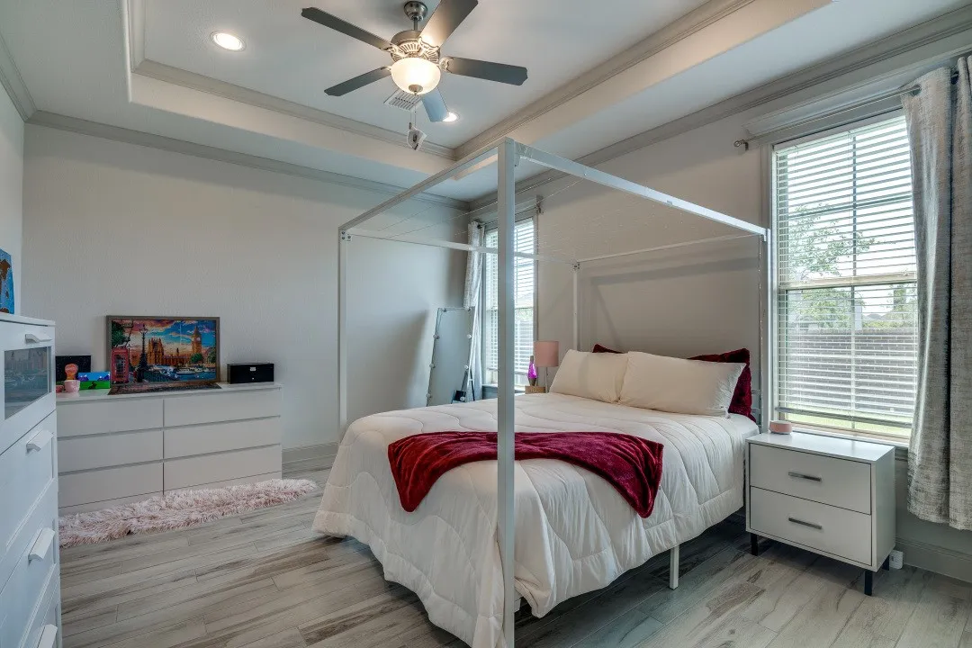 Tray ceiling with recessed lighting, ceiling fan, wood-finish flooring, and multiple windows