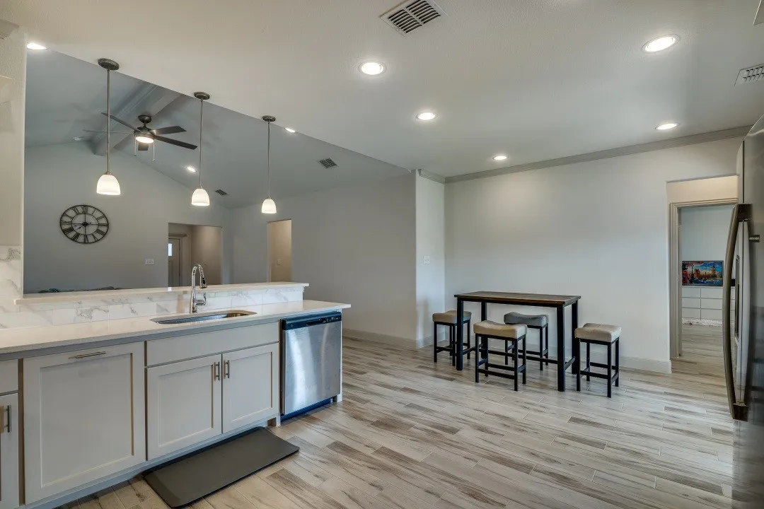 Kitchen with light-toned cabinetry, stainless steel dishwasher, and a white countertop with a matching backsplash