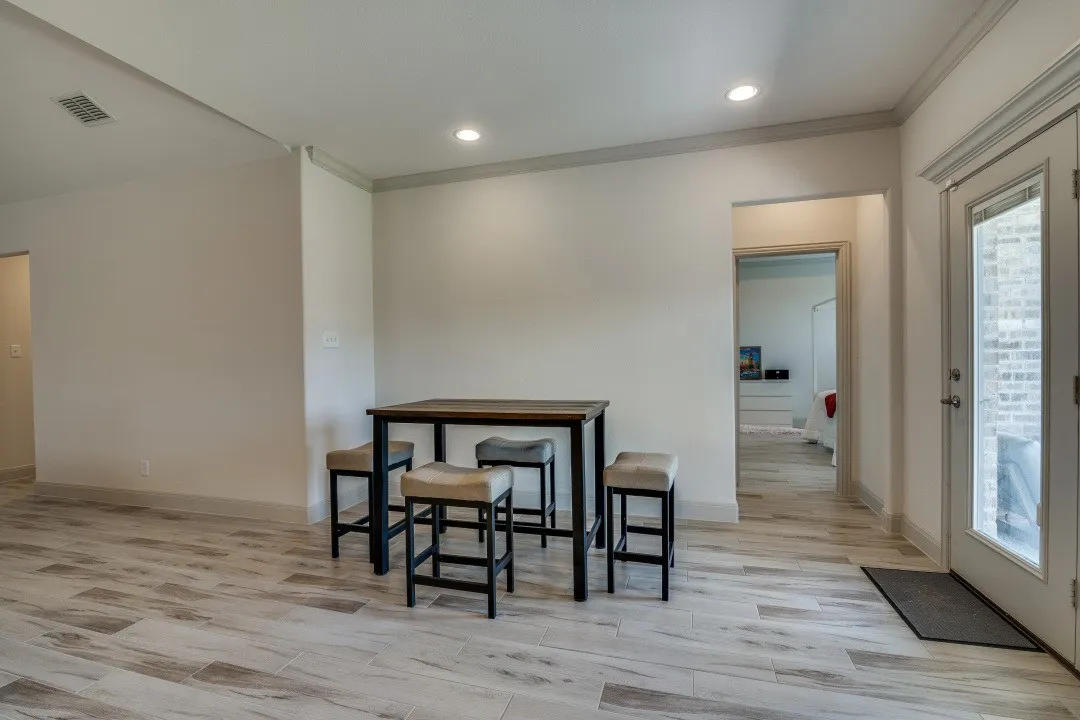 Recessed lighting, crown molding, wood-finish flooring, white walls, and a glass-paneled exterior door