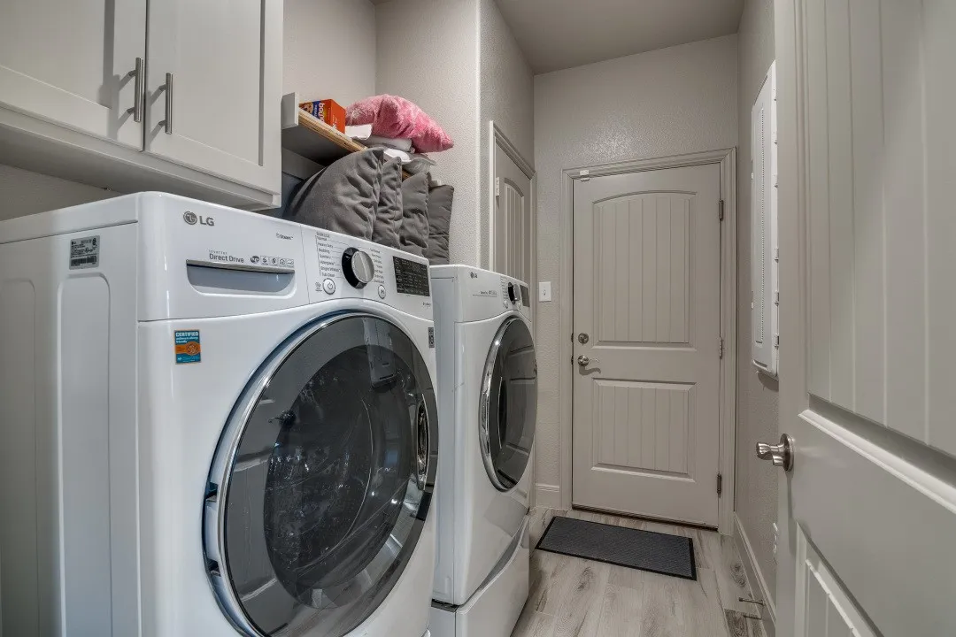 Laundry area featuring overhead cabinetry, a built-in shelf, and wood-finish flooring