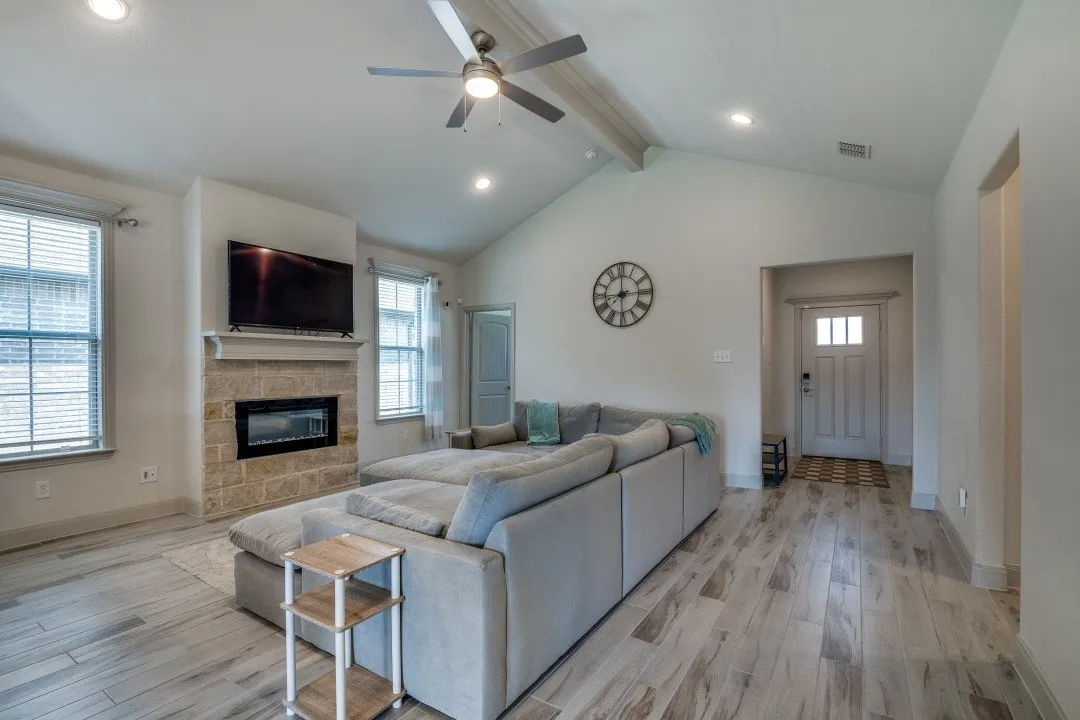 Spacious living area featuring a vaulted ceiling with a ceiling fan, recessed lighting, and wood-finish flooring