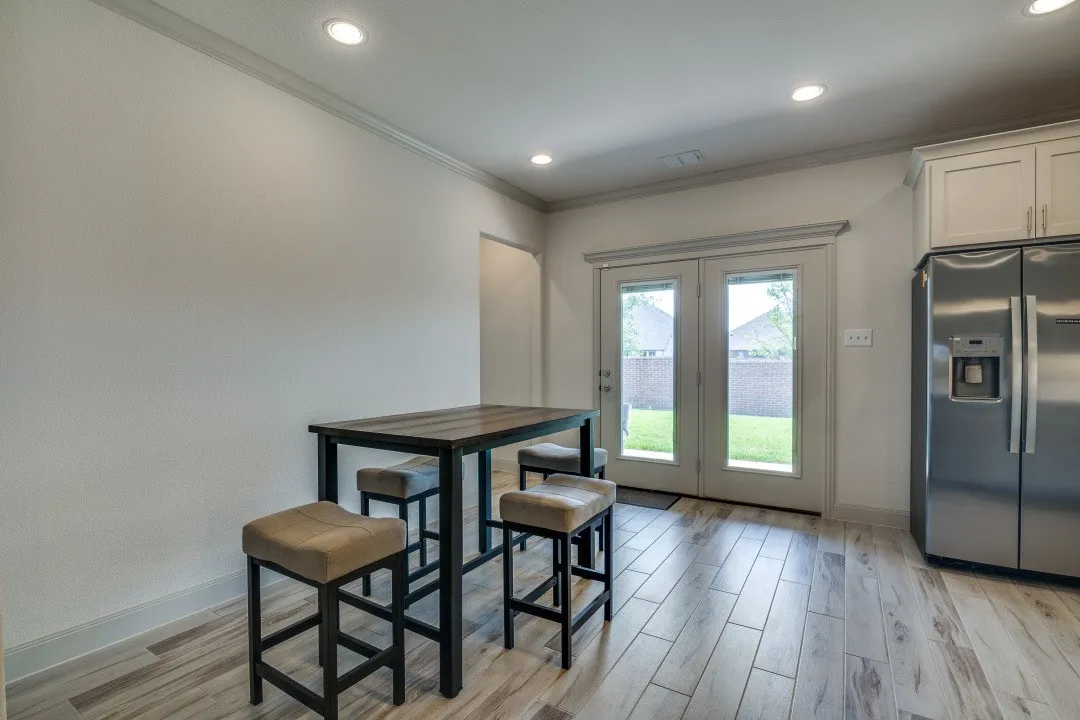 Recessed lighting, wood-finish flooring, French doors, stainless steel refrigerator, and upper cabinetry