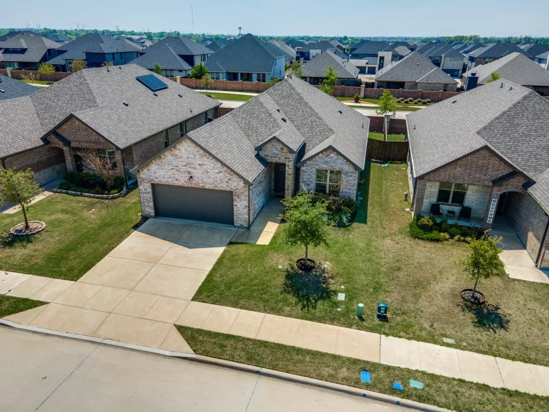 Brick and stone facade, attached garage, concrete driveway, and front lawn