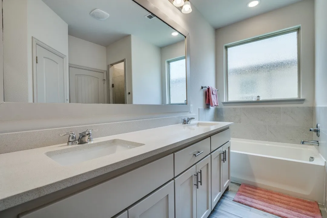 Dual vanity with integrated sinks, light-toned countertop, and recessed lighting