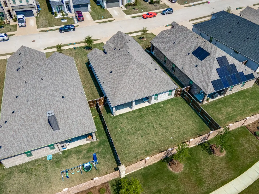Residential property featuring a shingle roof, a fenced backyard with a patio, and an adjacent property with solar panels